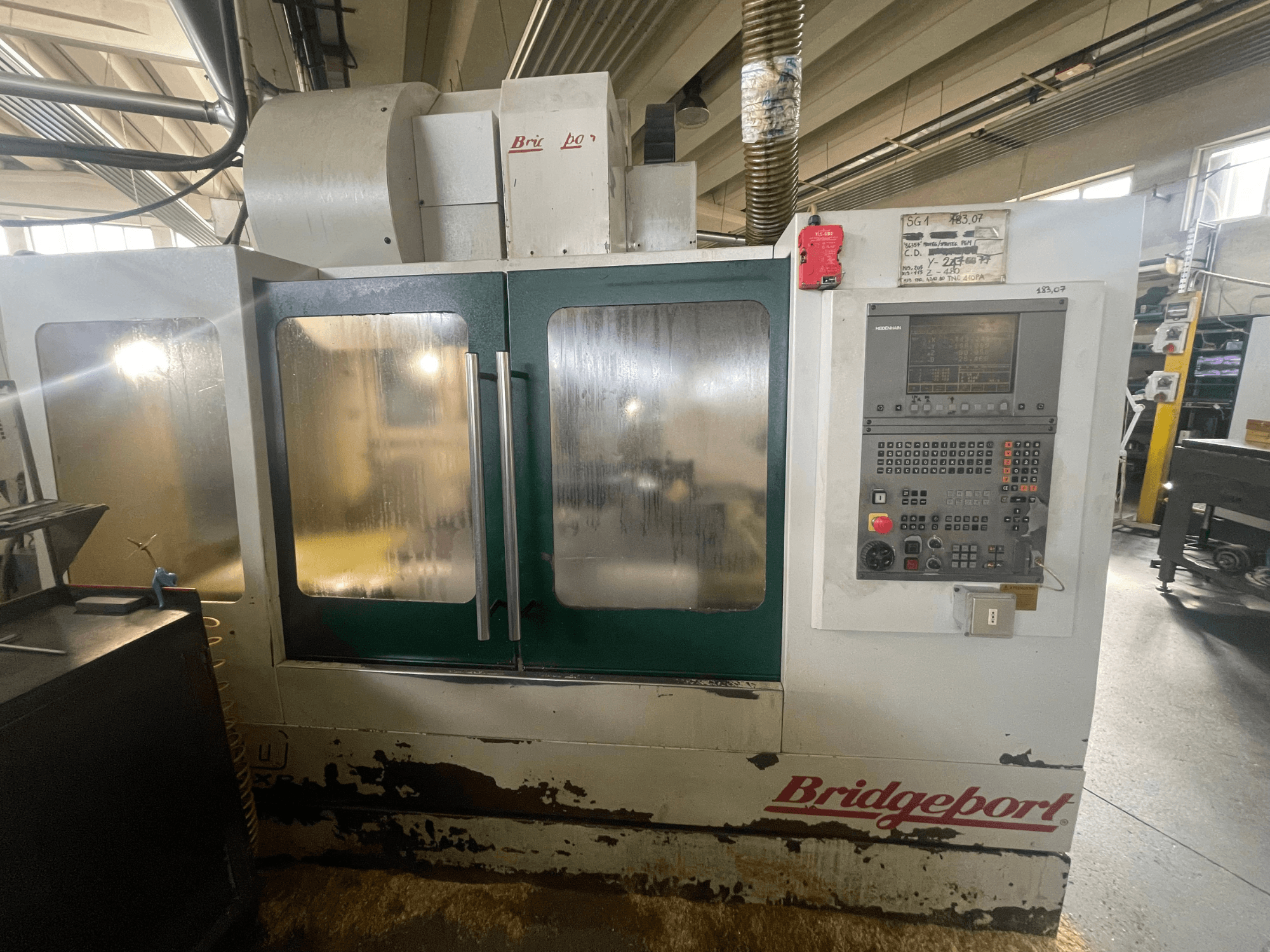 Bridgeport VMC 1000/30 vertical machining center, front view with control panel, showing worn exterior and green doors.