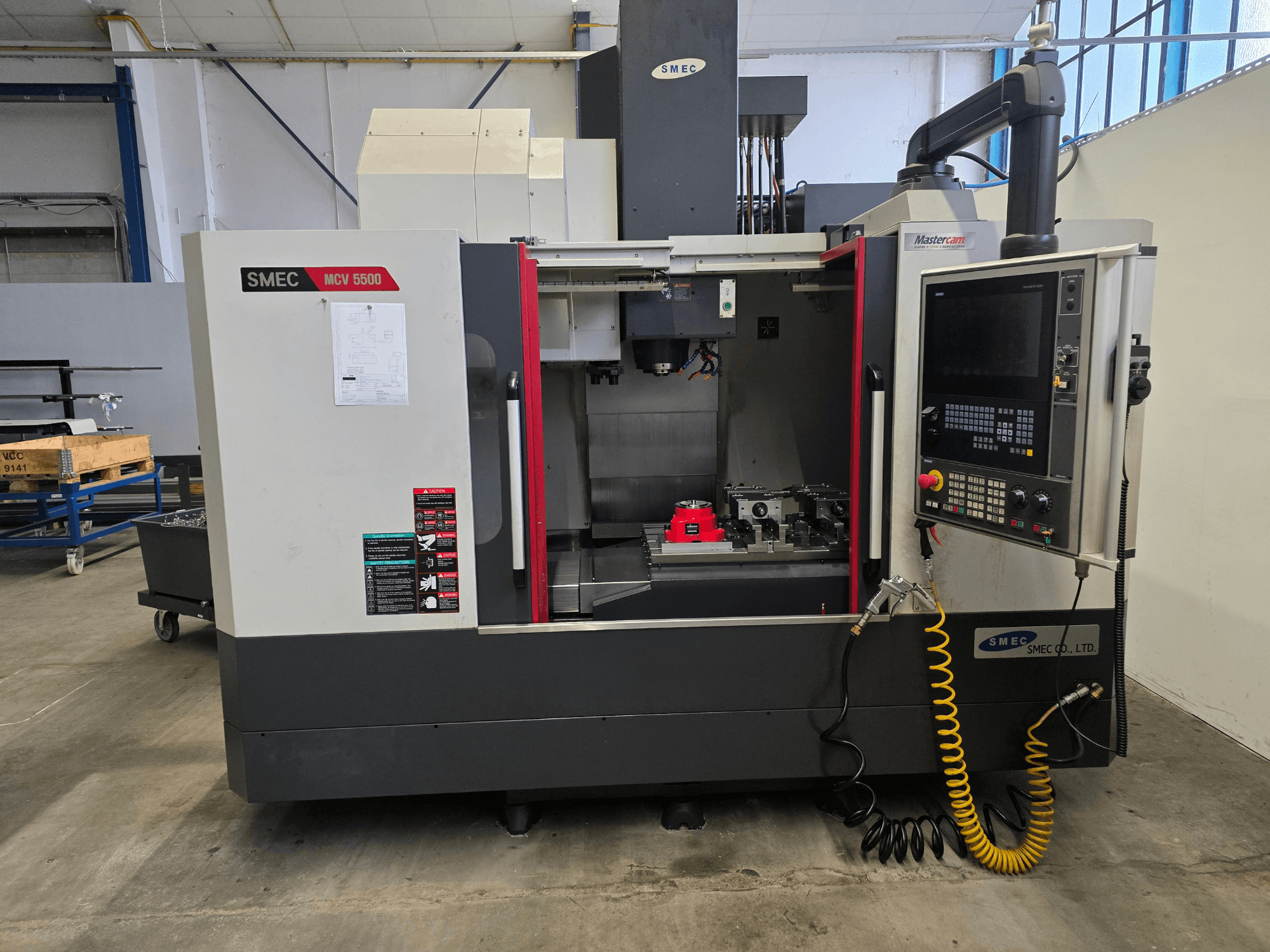 SMEC MCV 5500 vertical machining center, front view, showing control panel and machine interior with tools.