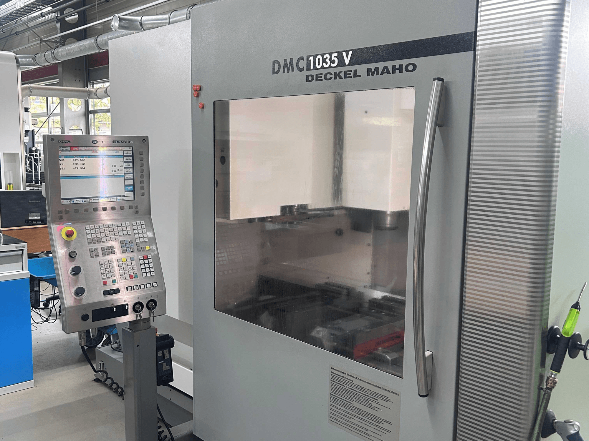 Front view of DECKEL MAHO DMC 1035 V vertical machining center, showcasing control panel and clear window to work area.