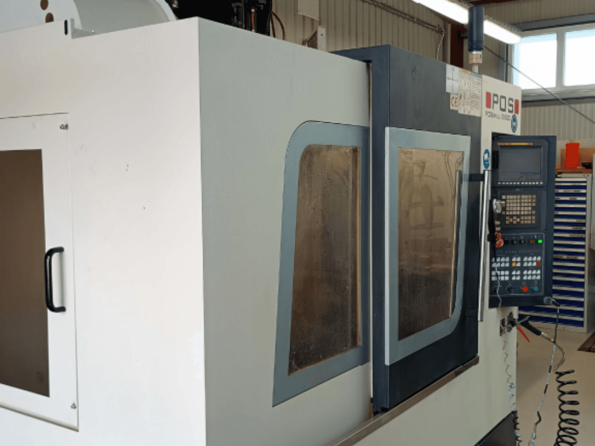 POSmill B 800 vertical machining centre shown from the front, featuring operational panels and safety glass windows.
