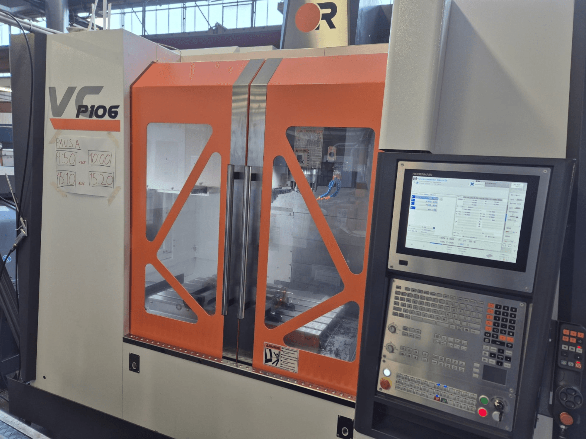 Alt text: Orange and gray VF P106 CNC machine, front view, displaying a control panel and scheduled operation times on paper.