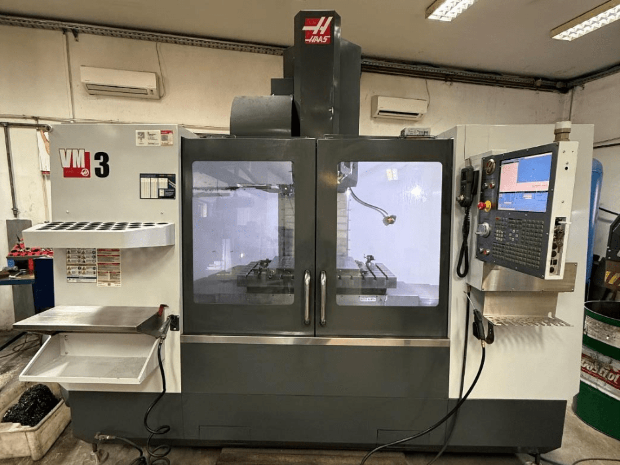 Haas VM-3 vertical machining center in front view, featuring a large control panel and visible work area with tools.