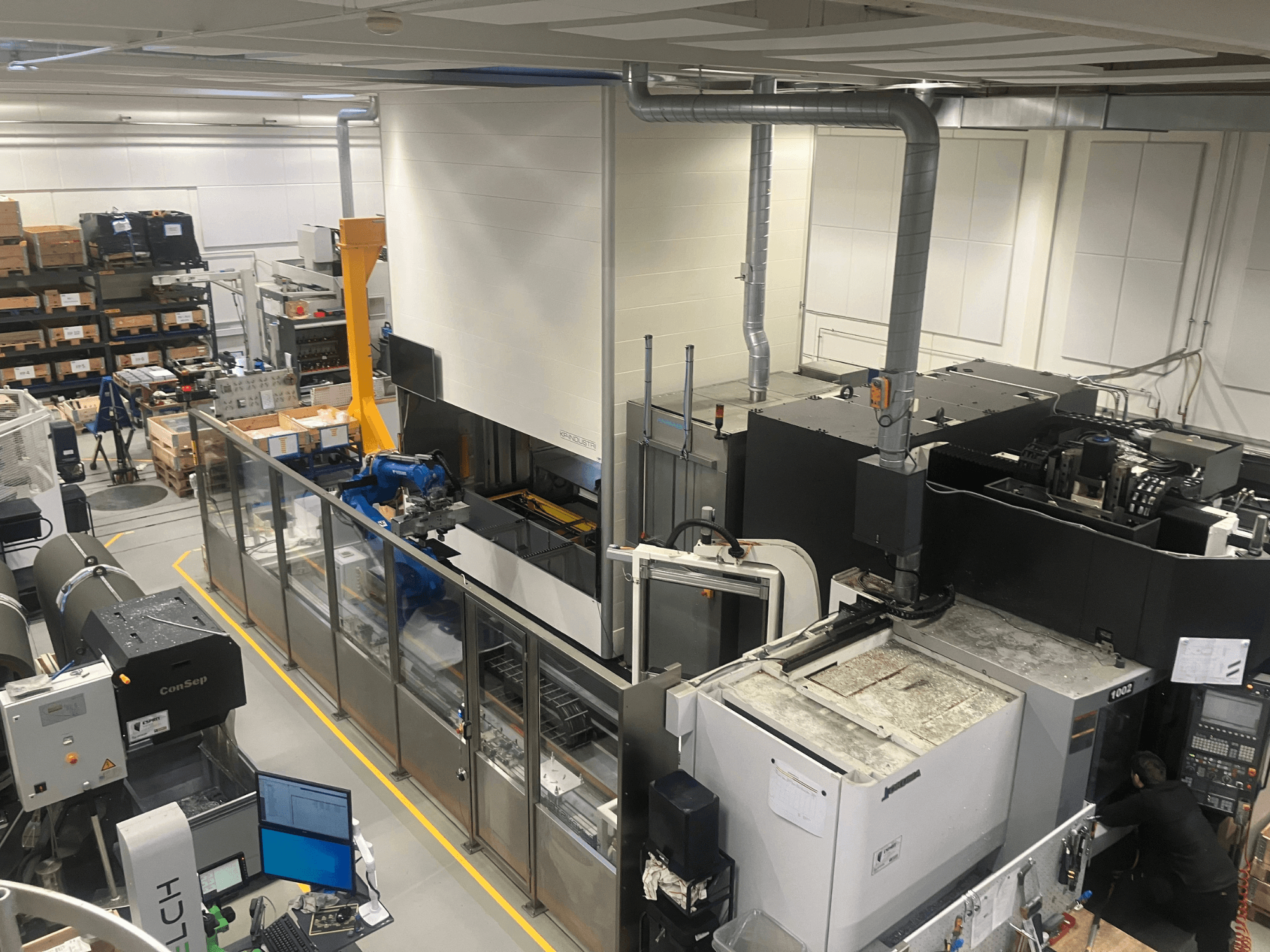 SSI SCHAFER Logimat automation system in a warehouse, front view; features robotic arm, storage racks, and machinery.