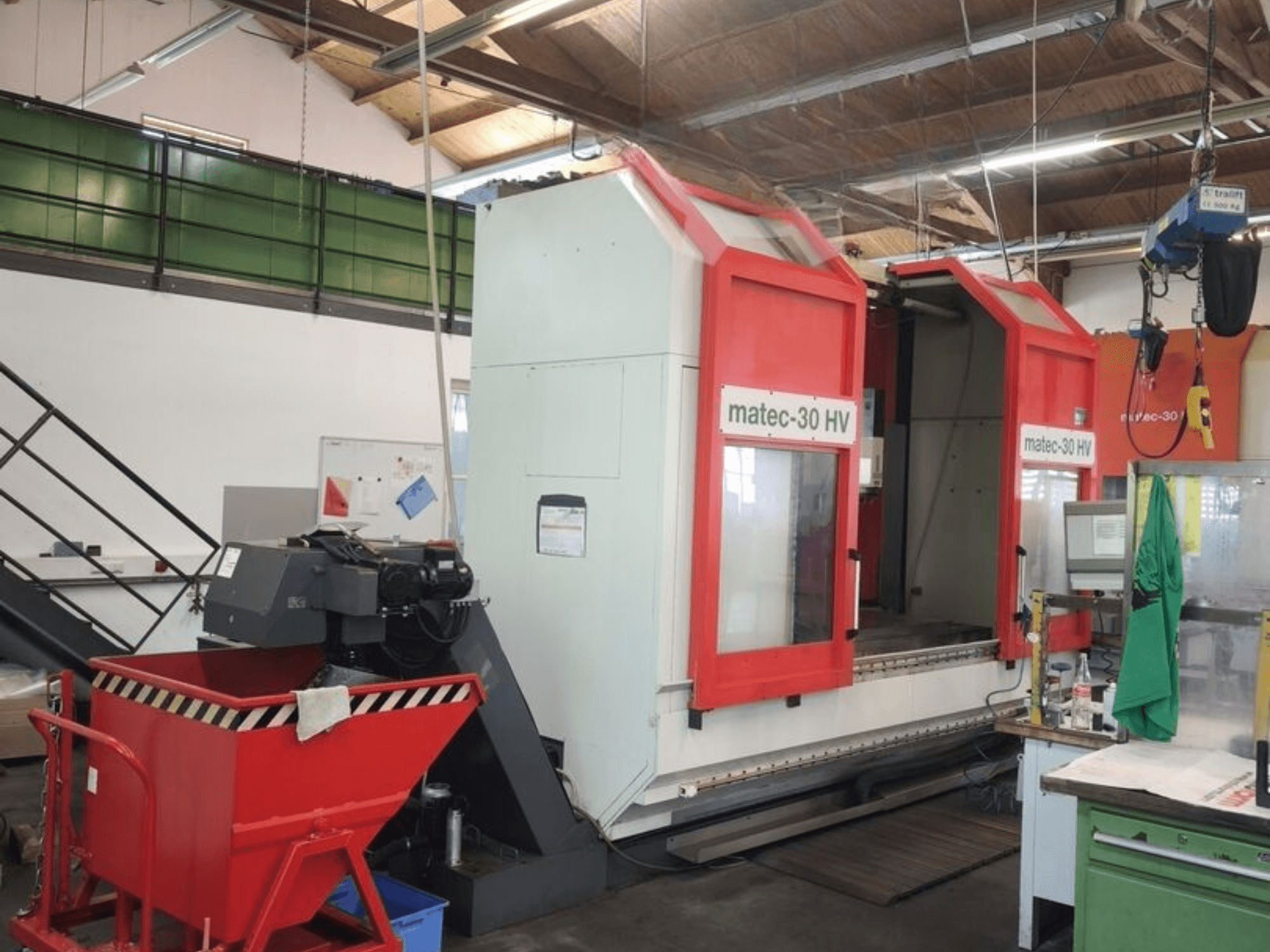 Red and white Matec HV30 universal machining center in a workshop, side view showcasing its large working area and controls.