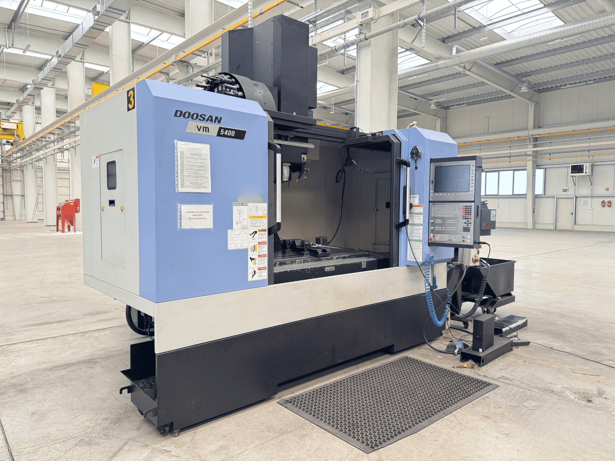 DOOSAN VM 5400 Vertical Machining Centre, front view showing control panel and work area in spacious industrial setting.
