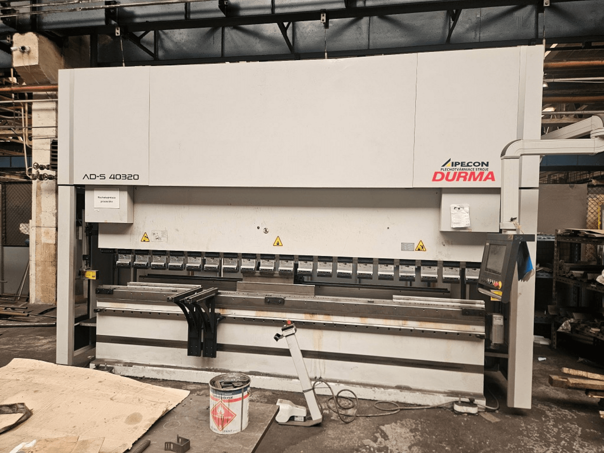 Durma AD-S 40320 press brake in front view, featuring control panel, bending tools, and safety warnings in a workshop setting.