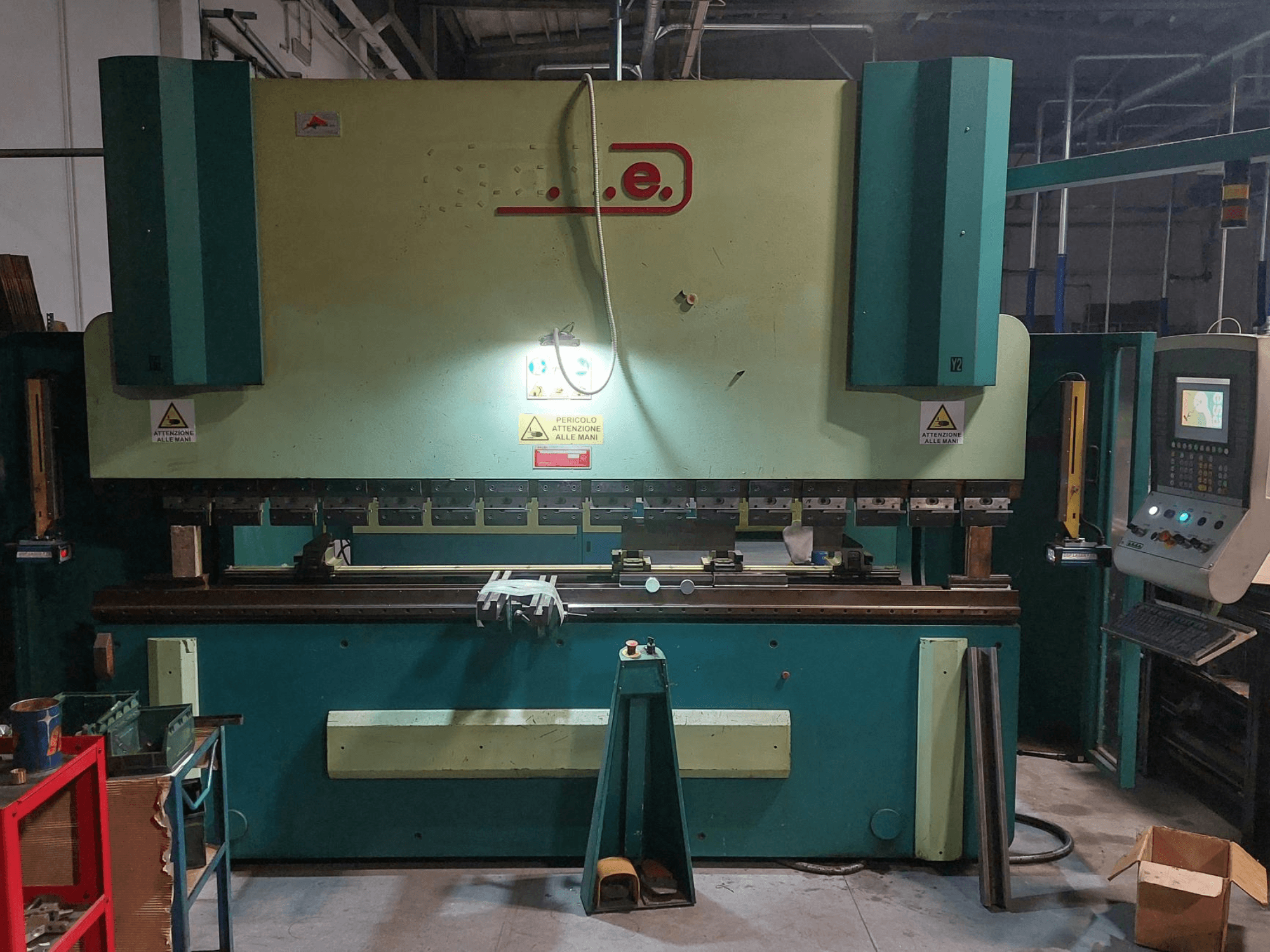 Front view of Gade PS-C 3120 press brake, featuring control panel, safety signs, and work area with tools and materials.