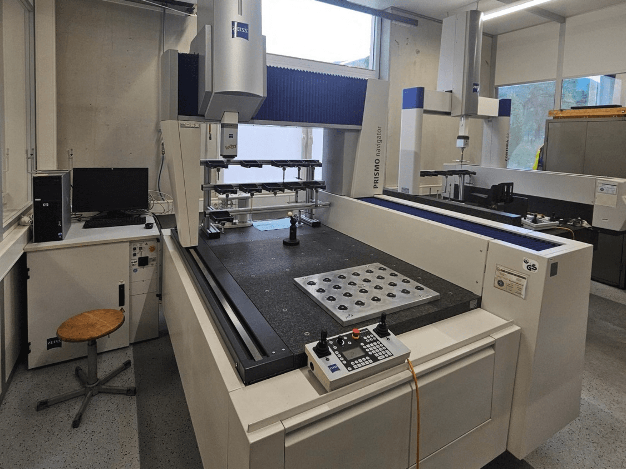 ZEISS Prismo Navigator 7 CMM in a lab, front view showing control panel, worktable, and monitor.