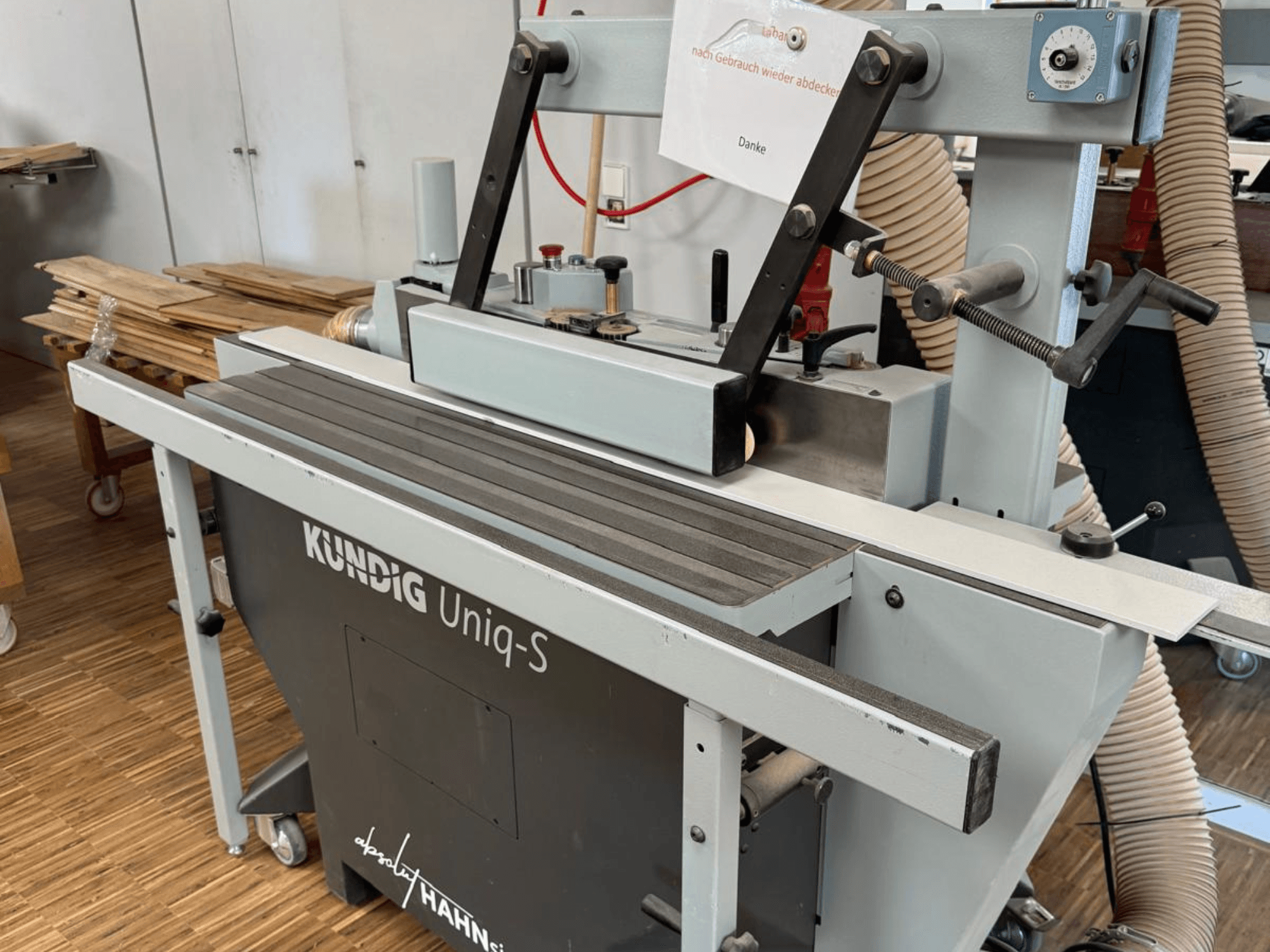 Kundig UNIQ-S belt sander in a workshop, side view showcasing the sanding belt and adjustable support arms.