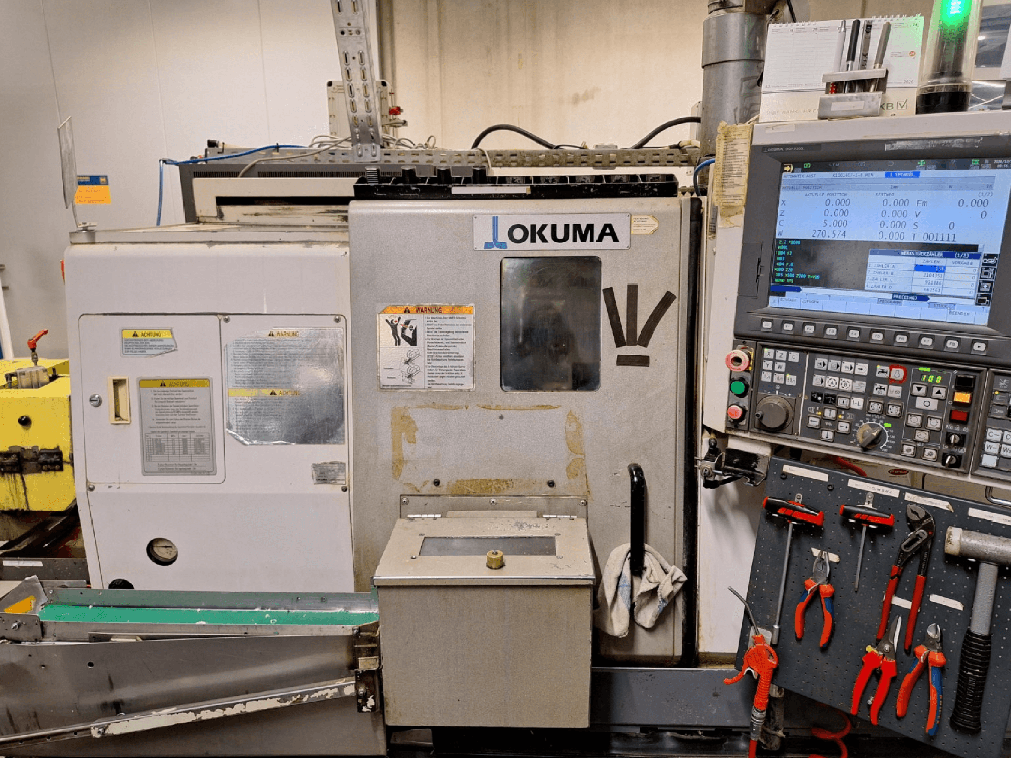 Okuma LB200-MW horizontal turning machine, front view, with control panel and tools visible on the side.