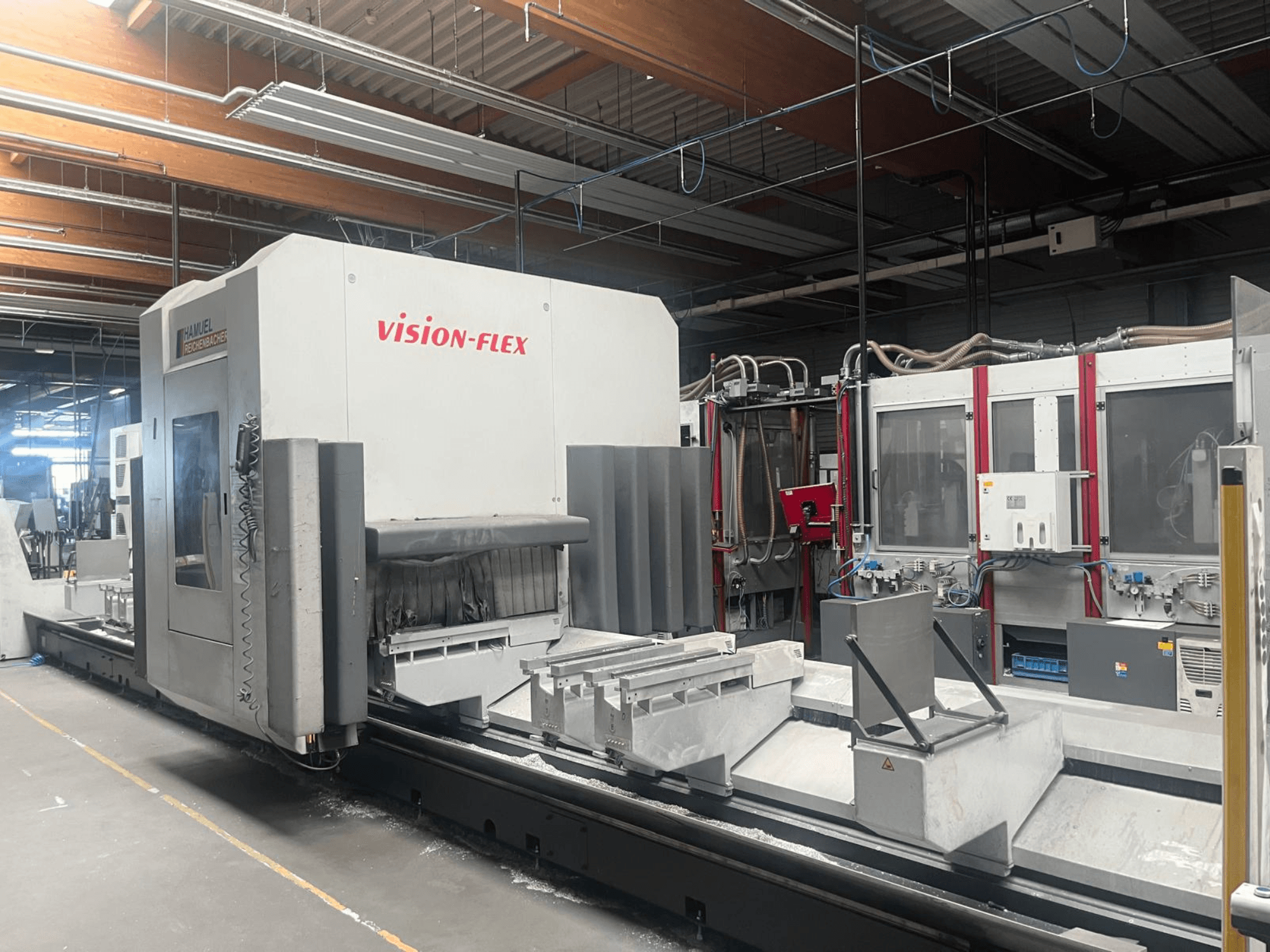 Vertical machining center, Hamuel Reichenbacher Vision Flex, side view showcasing work area and controls in an industrial setting.