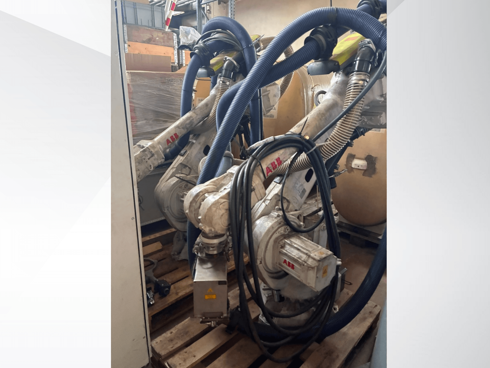 ABB IRB 4600-40/2.55 robot arm, side view showing dual arms and attached hoses, mounted on pallets in a warehouse setting.