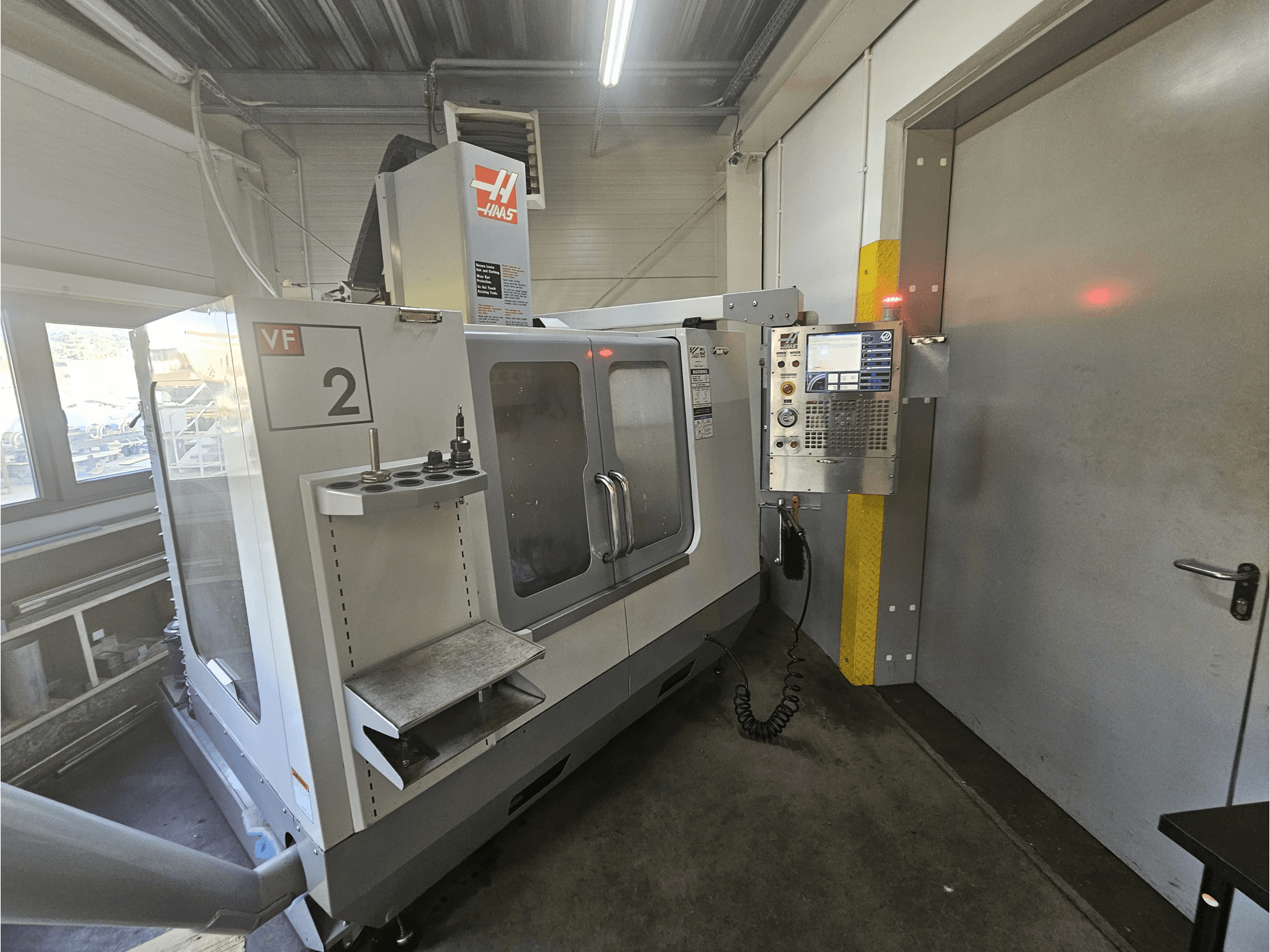 Haas VF-2 CNC milling machine, front view, showing control panel, tool holders, and a clear window on the workspace.
