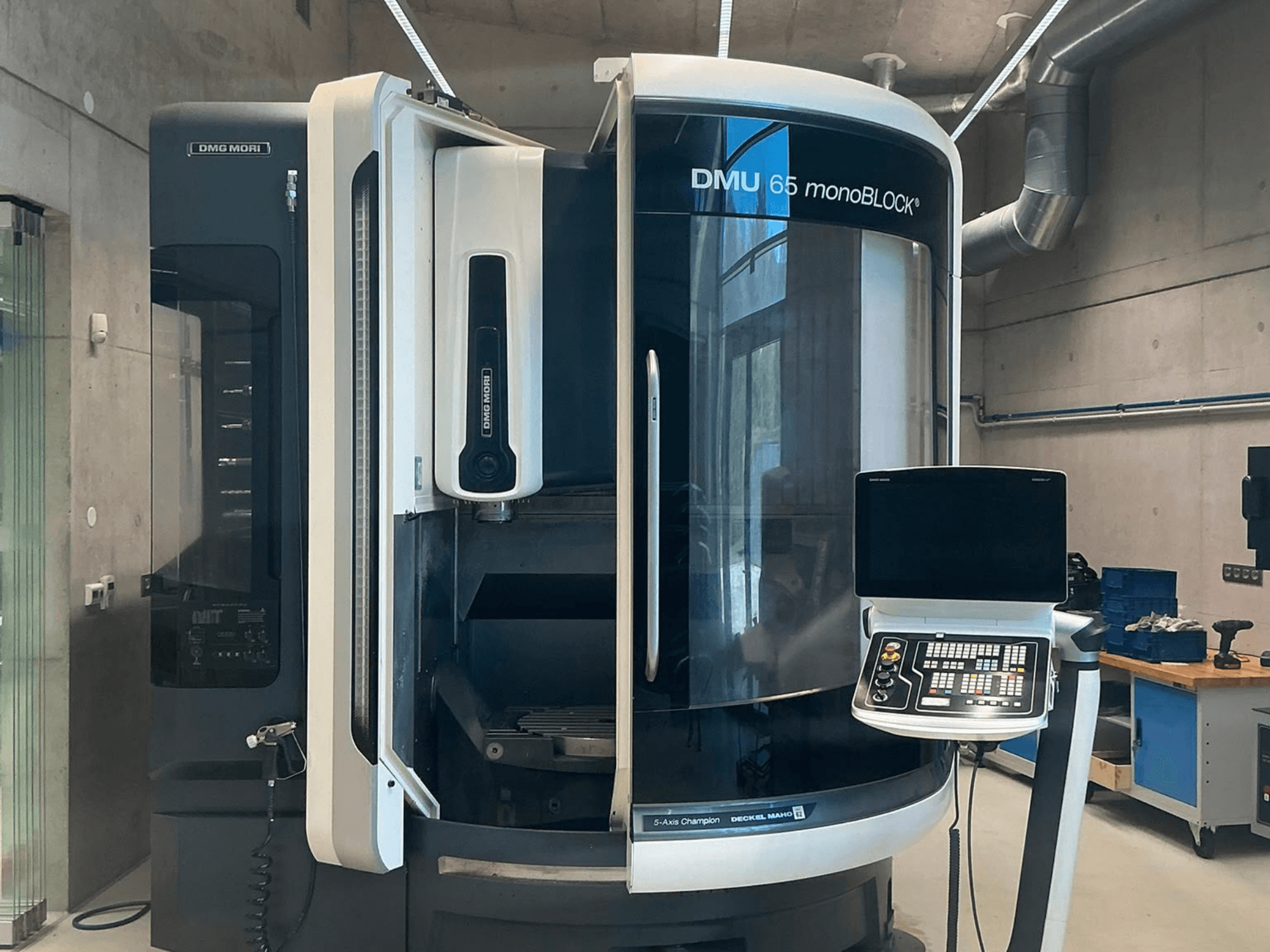 DMG MORI DMU 65 monoBLOCK vertical machining center, front view, showing control panel and machine details in a workshop setting.