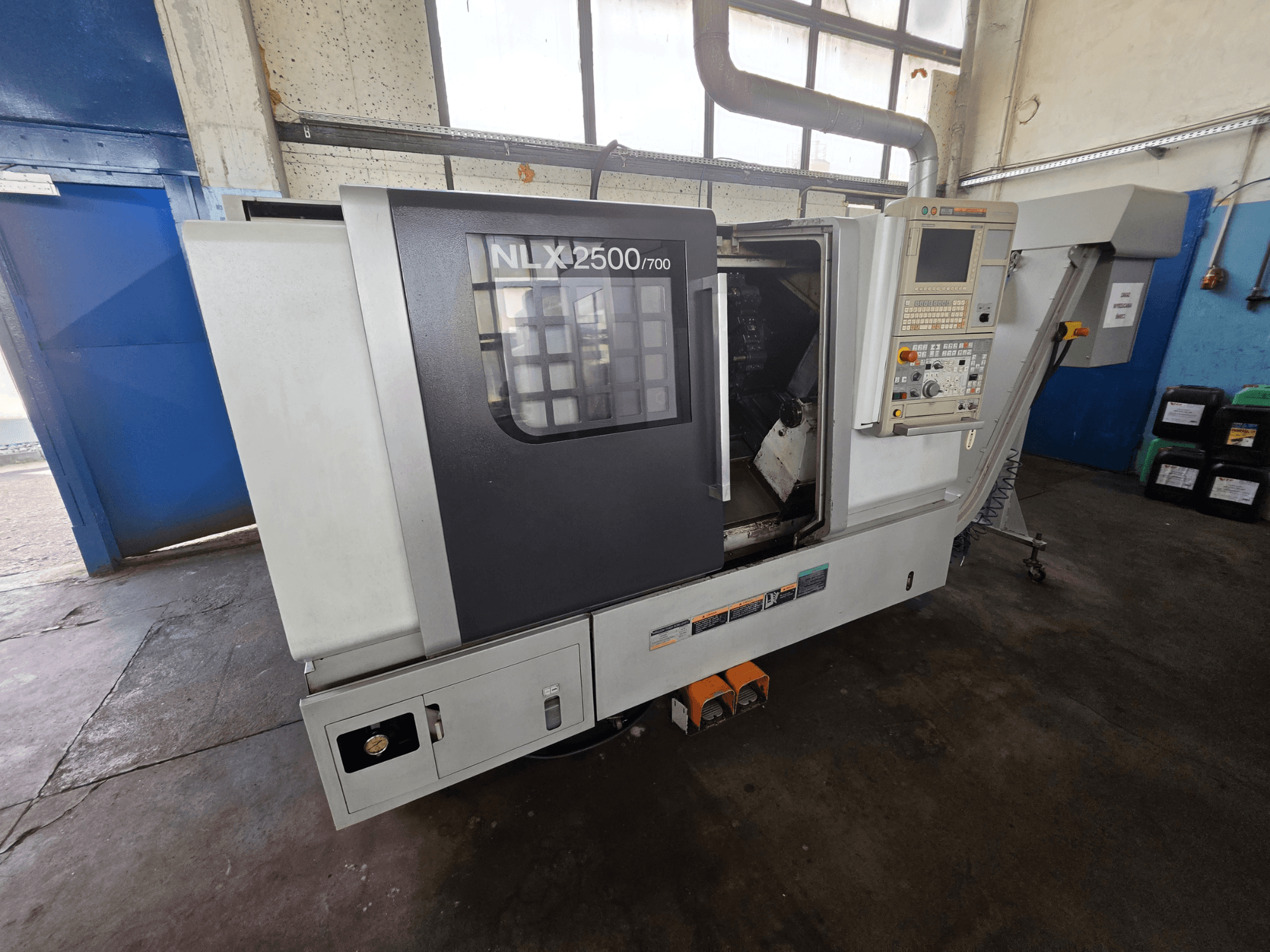 DMG MORI NLX 2500/700 horizontal turning machine in side view, featuring control panel and visible machining area.