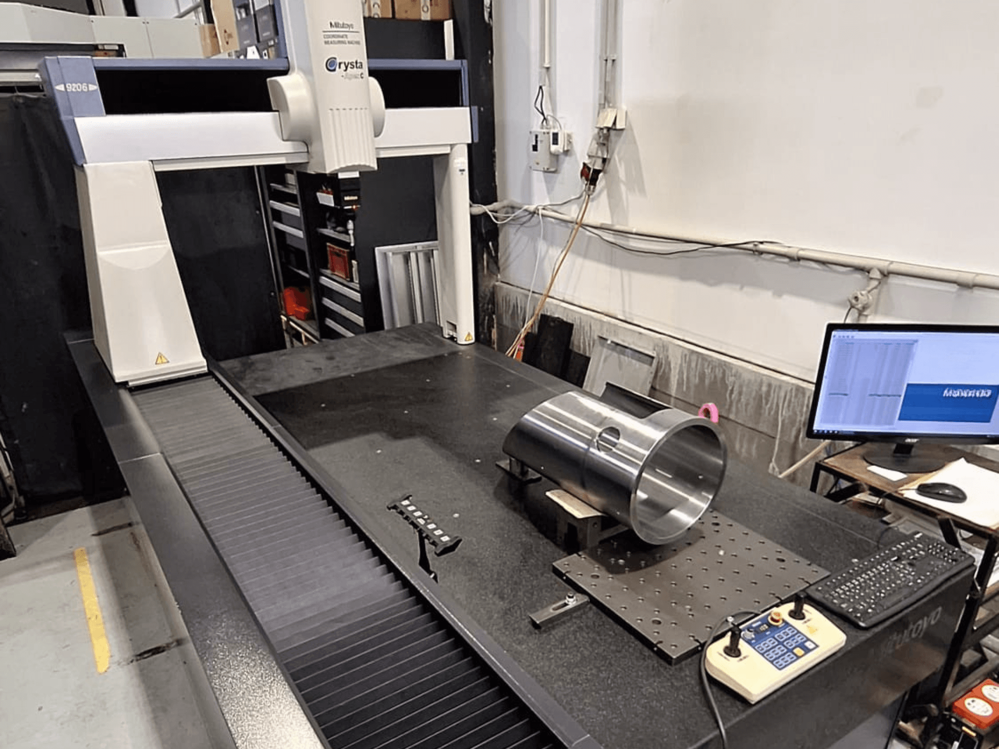 Mitutoyo Crysta-Apex C9206 CMM in front view, measuring a cylindrical metal part on a black granite surface plate.
