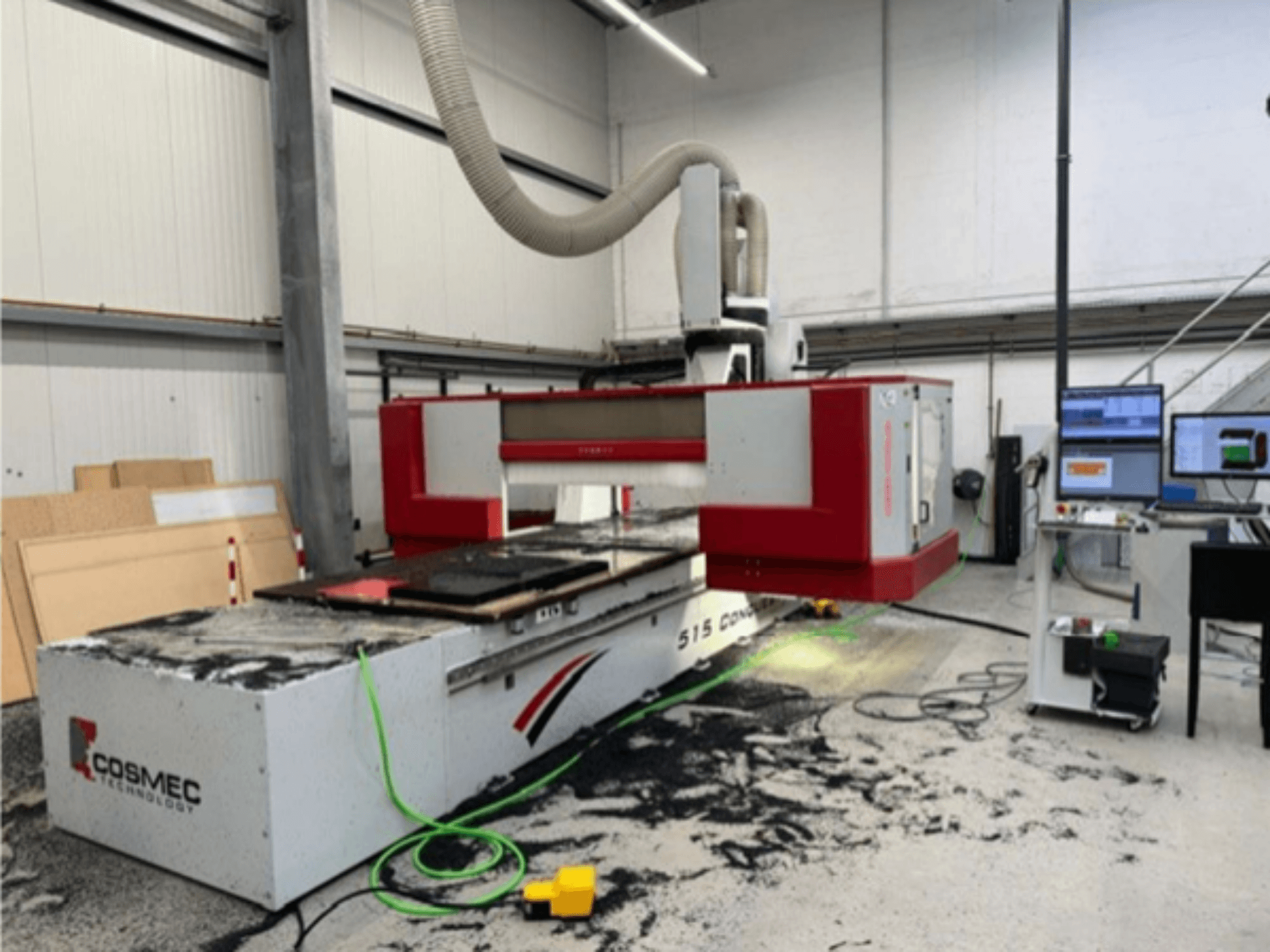 Cosmec 515 CNC machine in workshop with a computer terminal, showing a front view and dust scattered on the surface.