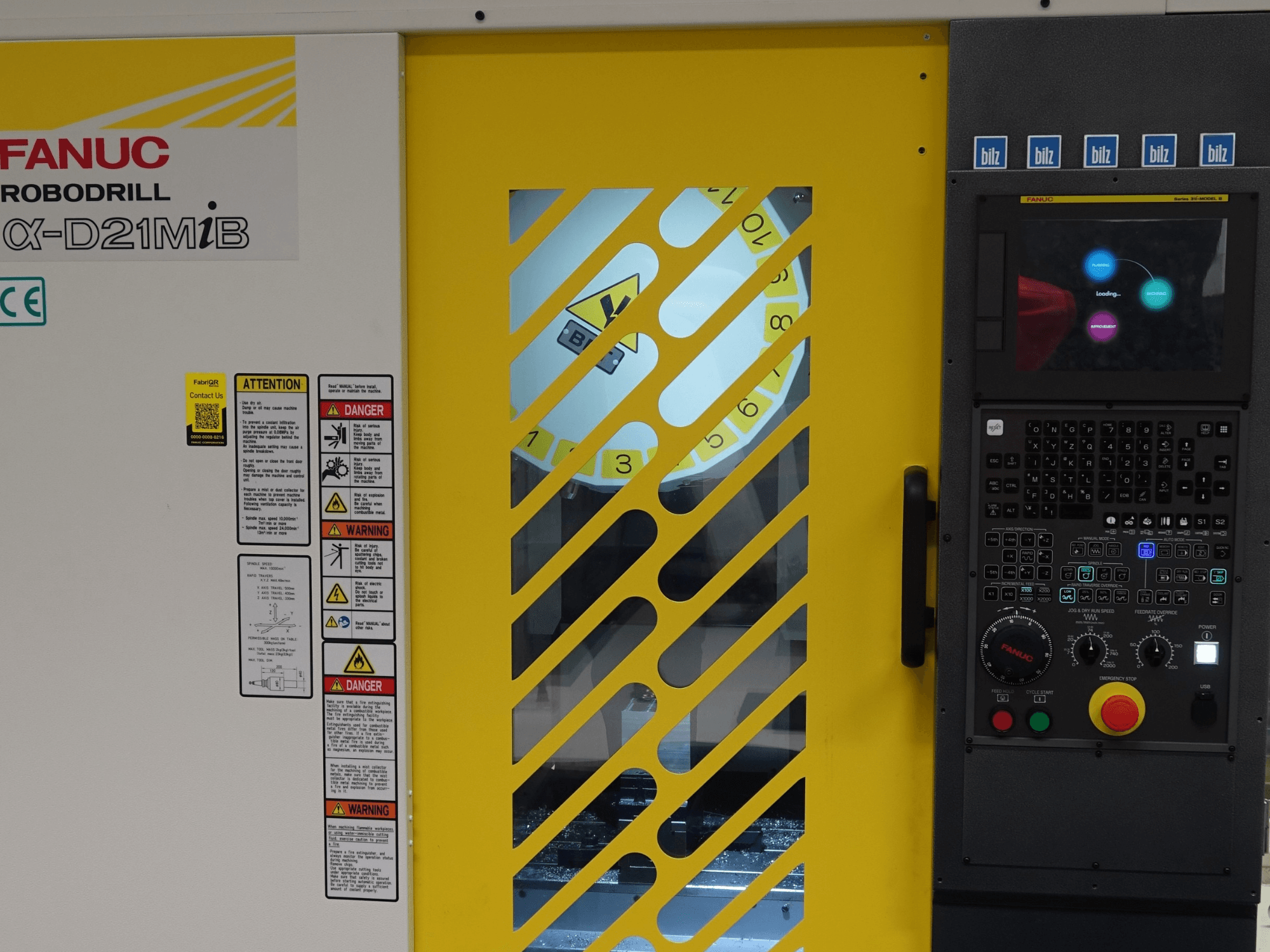 FANUC α-D21MiB Vertical Machining Centre front view, displaying safety warnings, control panel, and yellow safety door.