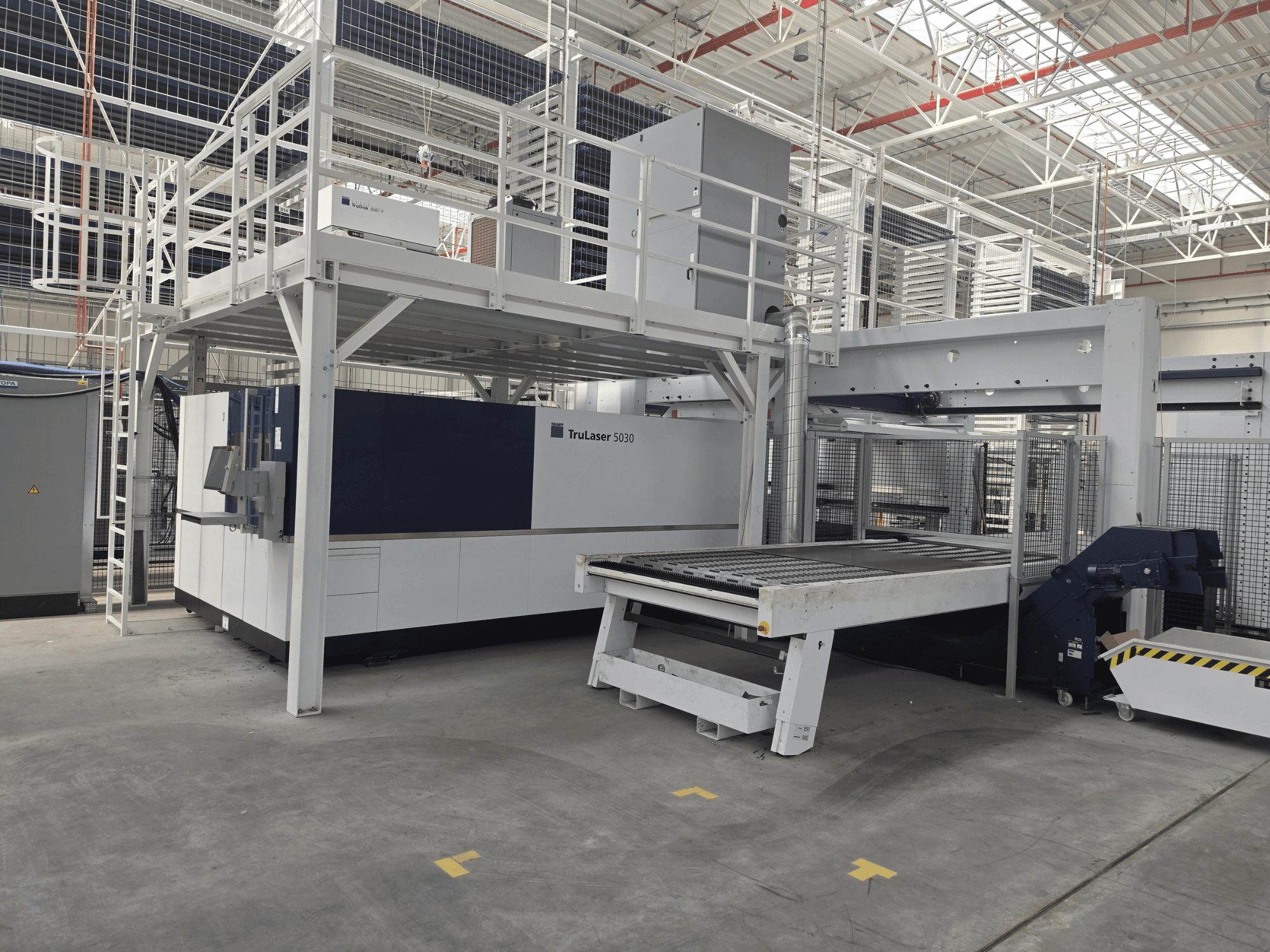 TRUMPF TruLaser 5030 fiber L76 FMC machine in a workshop, front view showing cutting area and loading/unloading mechanism.