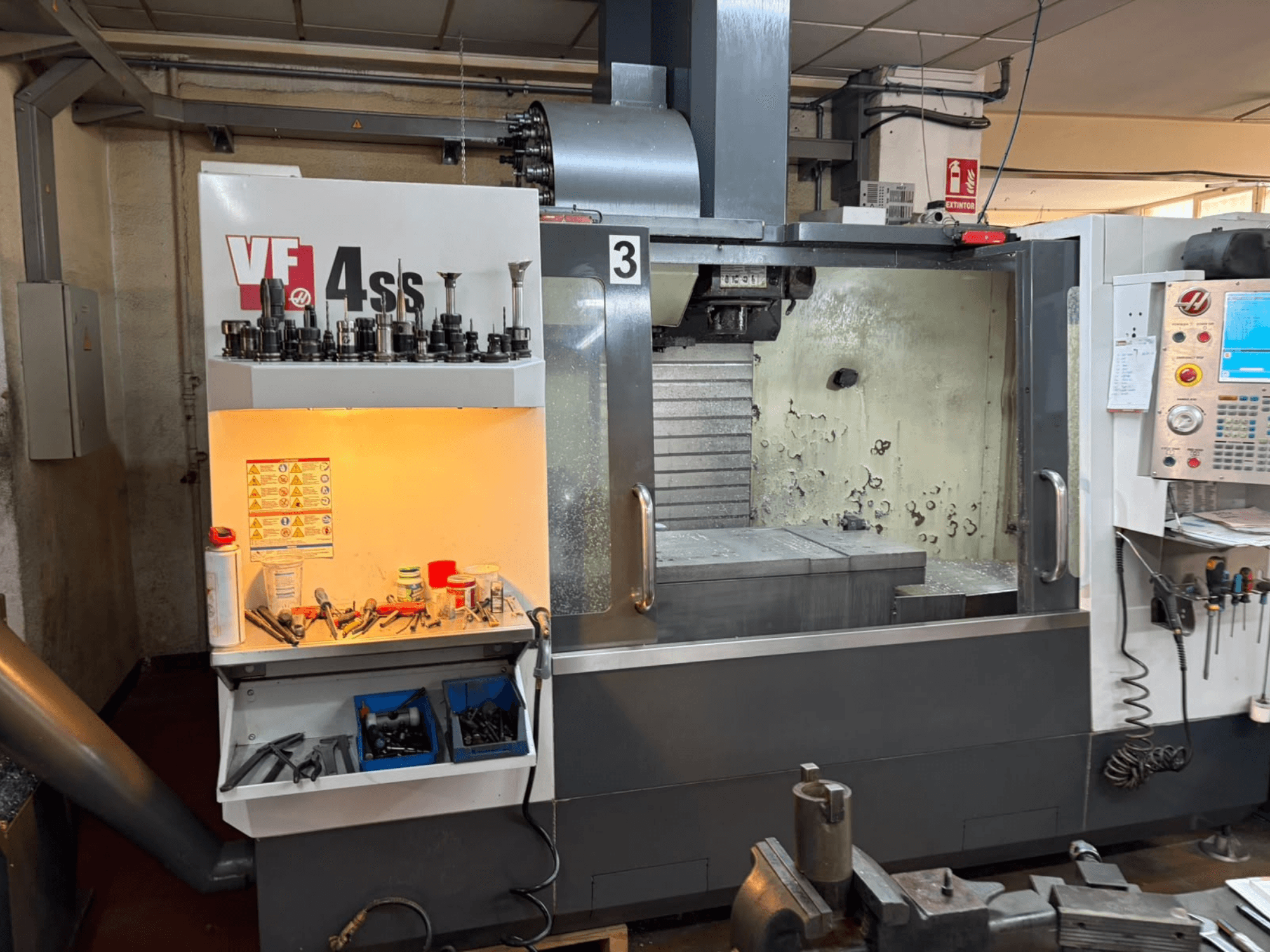 HAAS VP 4SS vertical machining center, front view, featuring tool storage, control panel, and visible work area with machining details.