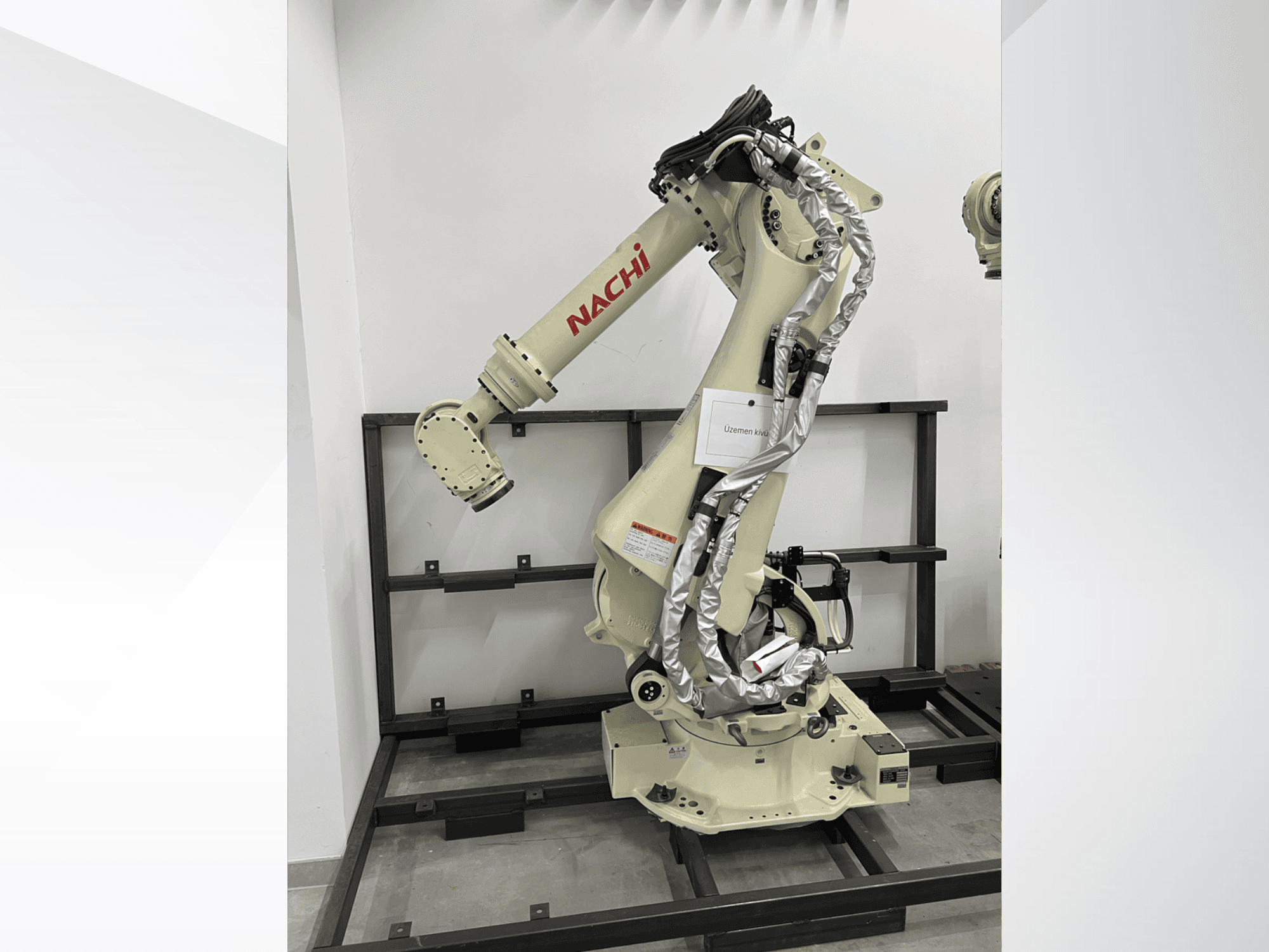 NACHI SRA166-01 robot arm in side view, featuring flexible joints, attached cables, and mounted on a protective frame.
