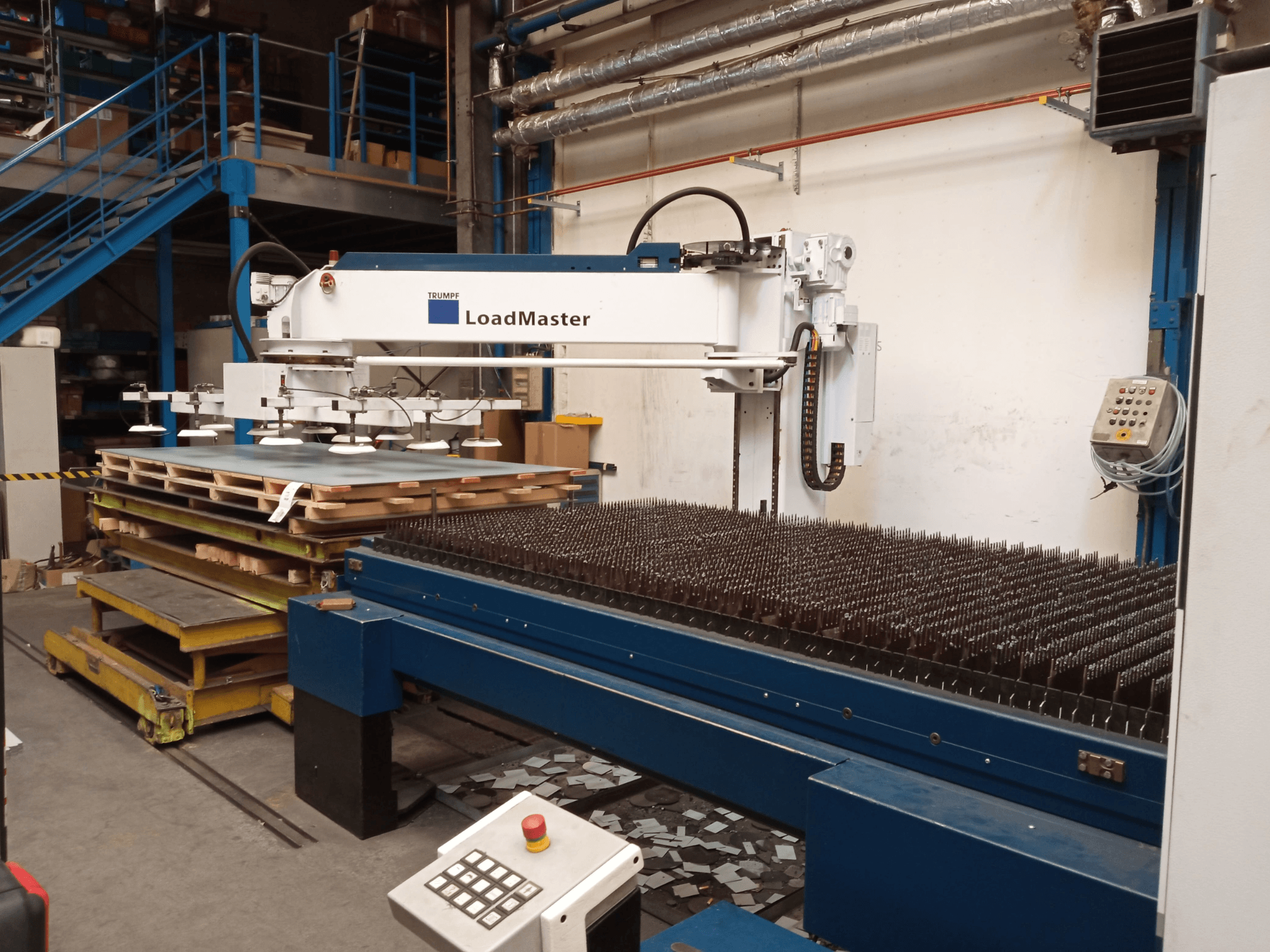 TRUMPF TruLaser 3030 CO2 laser cutting machine in a side view, featuring a LoadMaster and pallets of materials.
