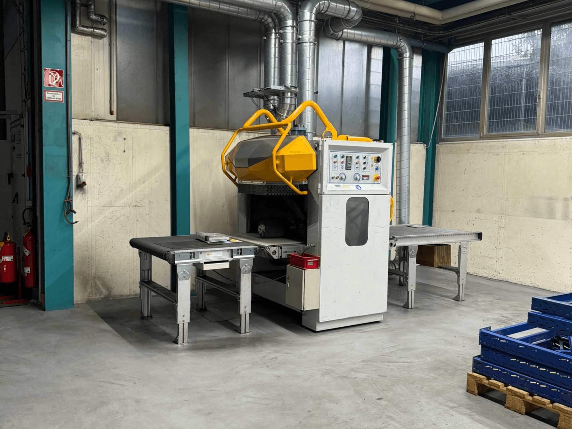 Deburring machine Fladder AUT-1000 VAC in a factory setting, featuring control panel, yellow safety guard, and adjacent work tables.