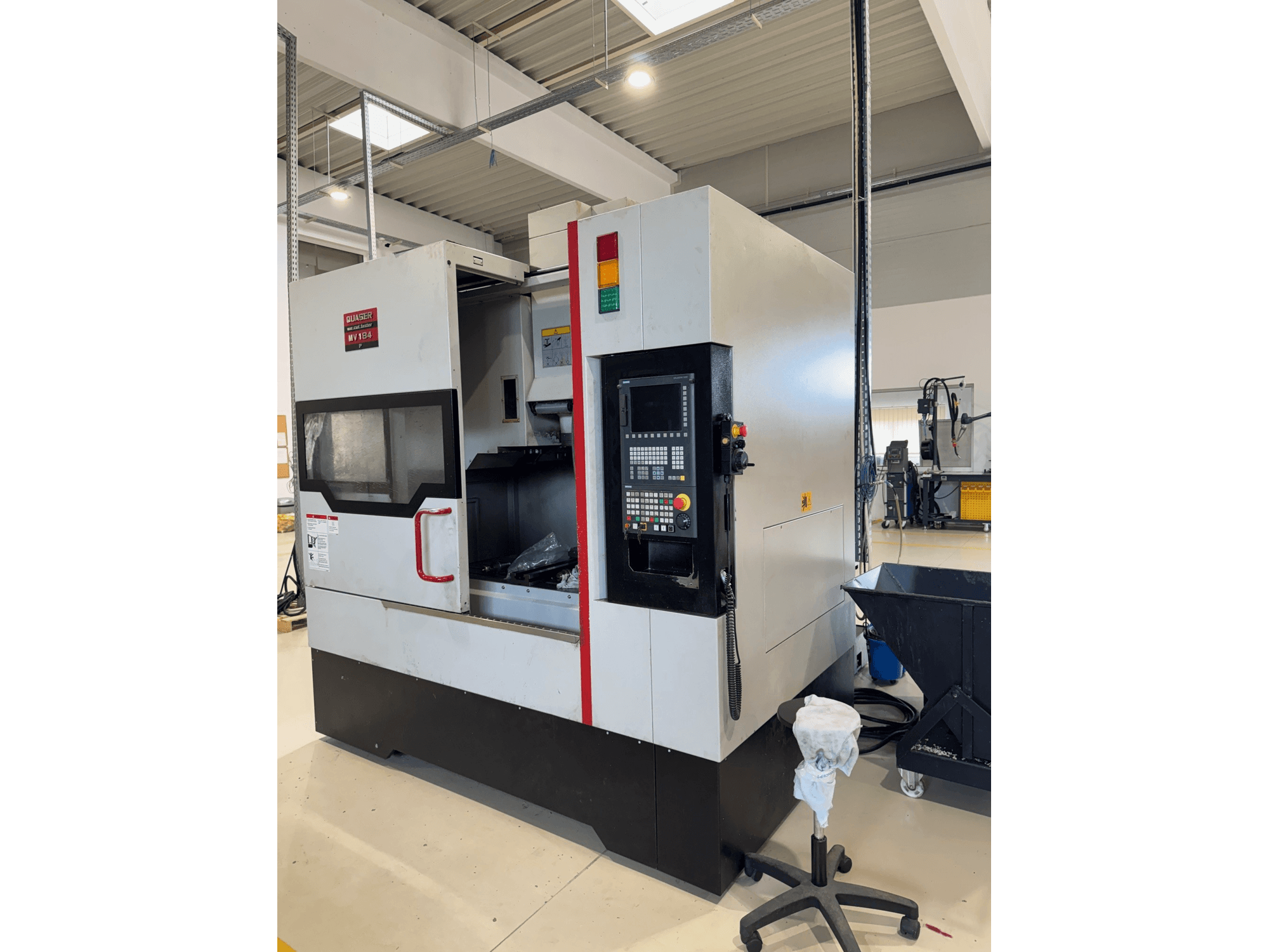 Quaser MV184P/12B vertical machining centre, side view, showcasing control panel and open front with machining area visible.