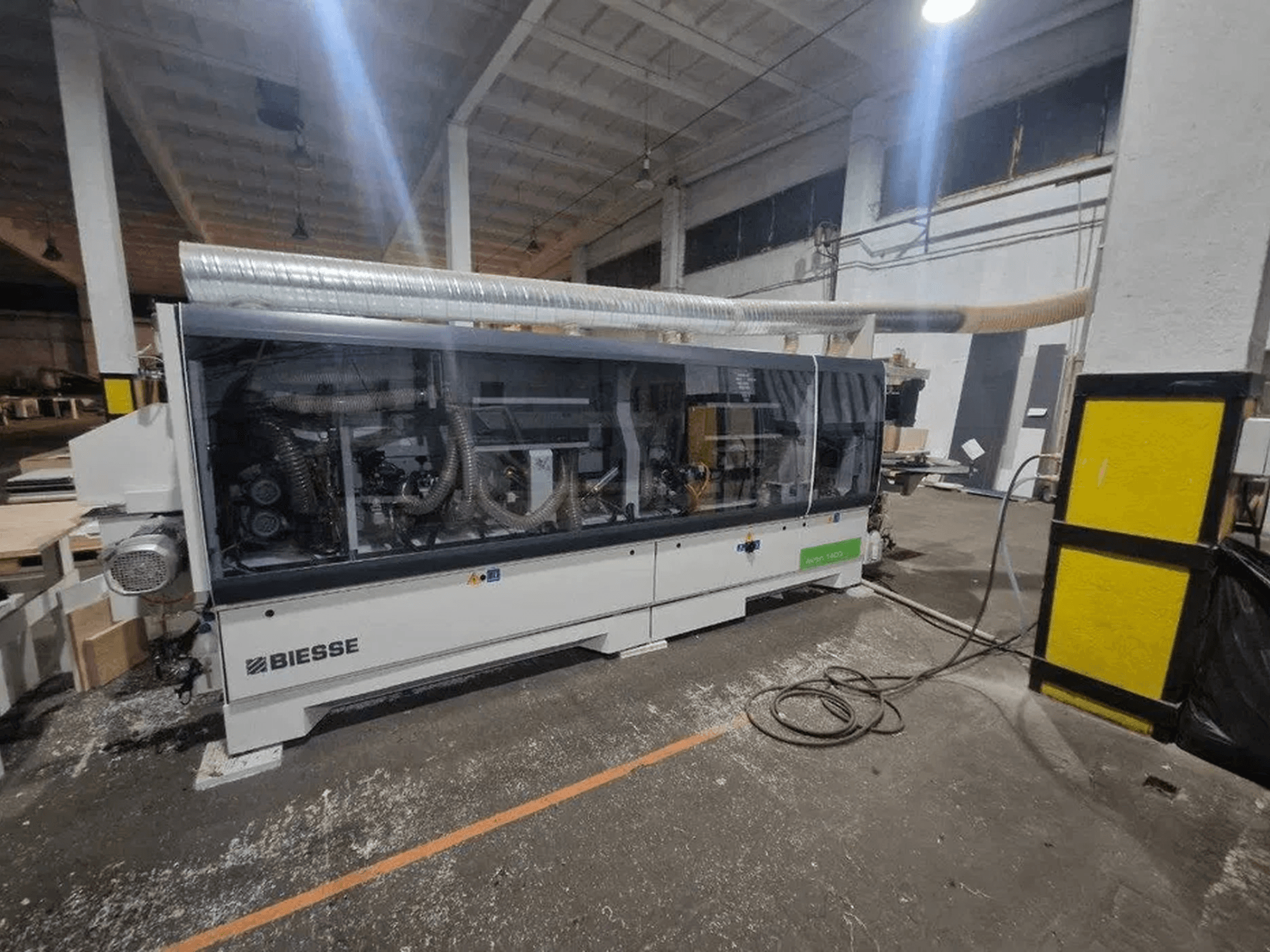 BIESSE Akron 1440 A edgebander in a workshop, featuring a transparent cover and visible machinery components.