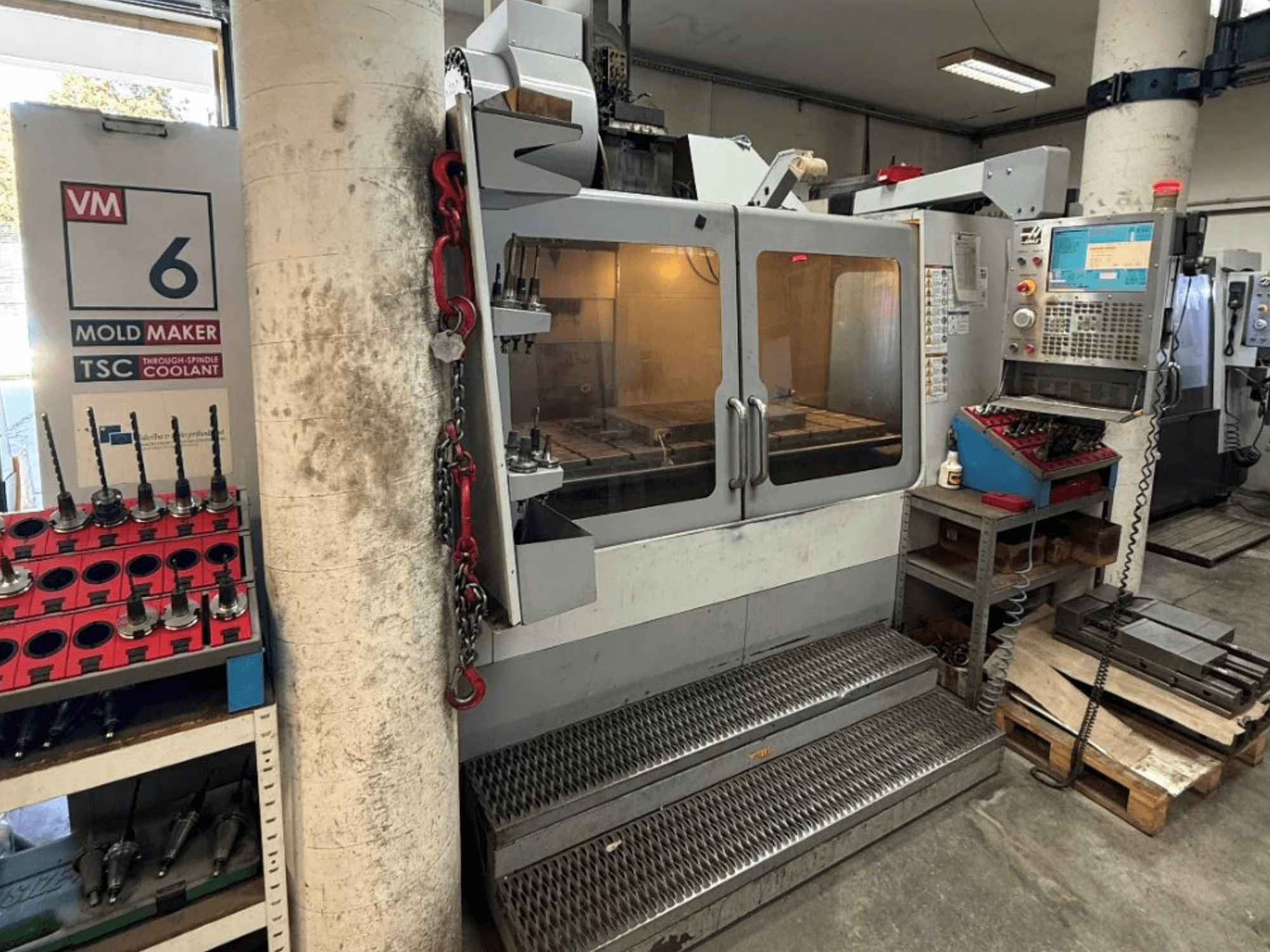 HAAS VM-6 HE vertical machining center in front view with controls, coolant system, and tool storage visible.