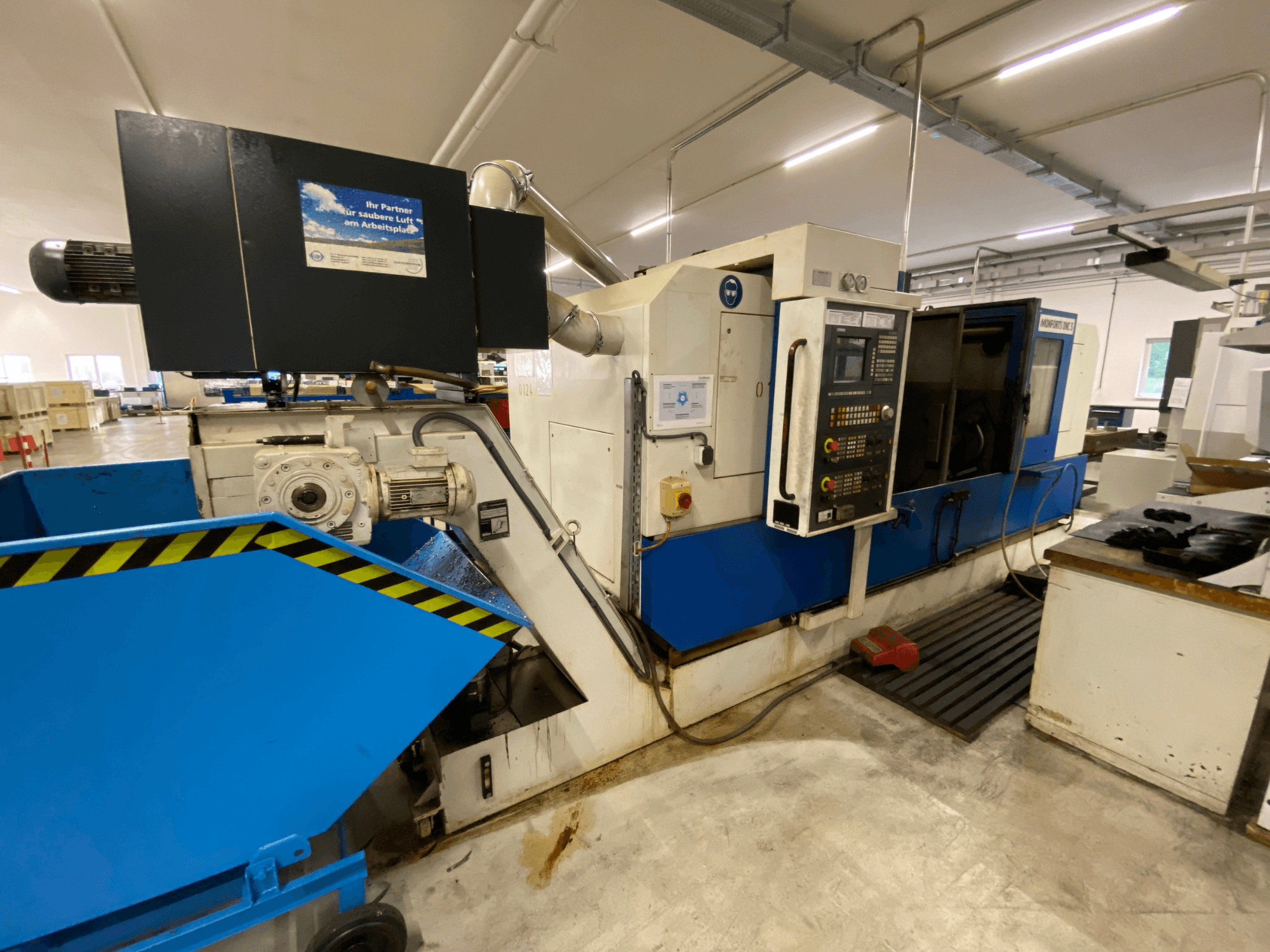 Monforts DNC 5 Turn-Mill Centre, side view showing control panel, blue chip tray, and machinery details in a workshop setting.