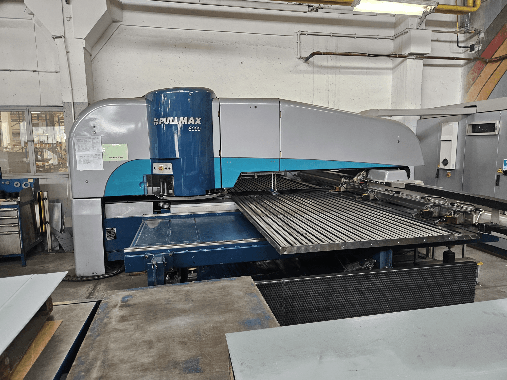 Front view of Pullmax 6000 CNC Punching Machine, showcasing its large flatbed and metal framework in a workshop setting.