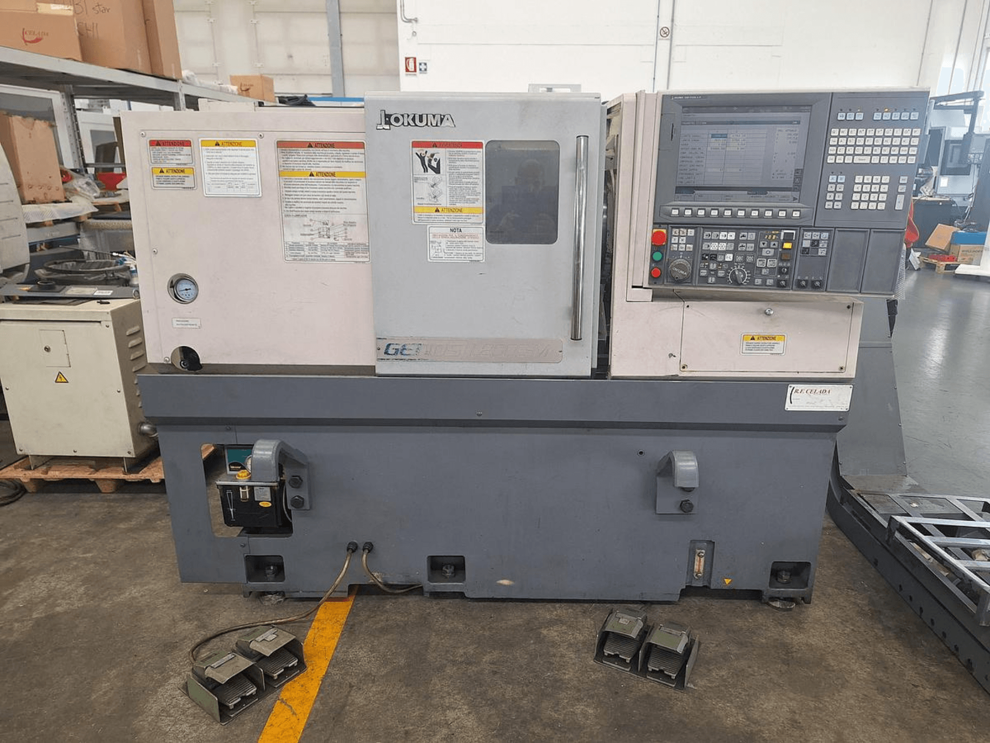 Okuma GENOS L200E-M horizontal turning machine in a side view; features control panel, safety warnings, and foot pedals.