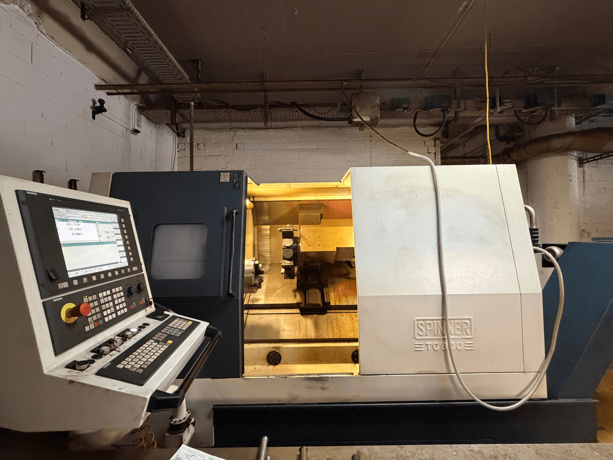 SPINNER TC800 horizontal turning machine in a workshop, featuring a control panel and visible internal components.