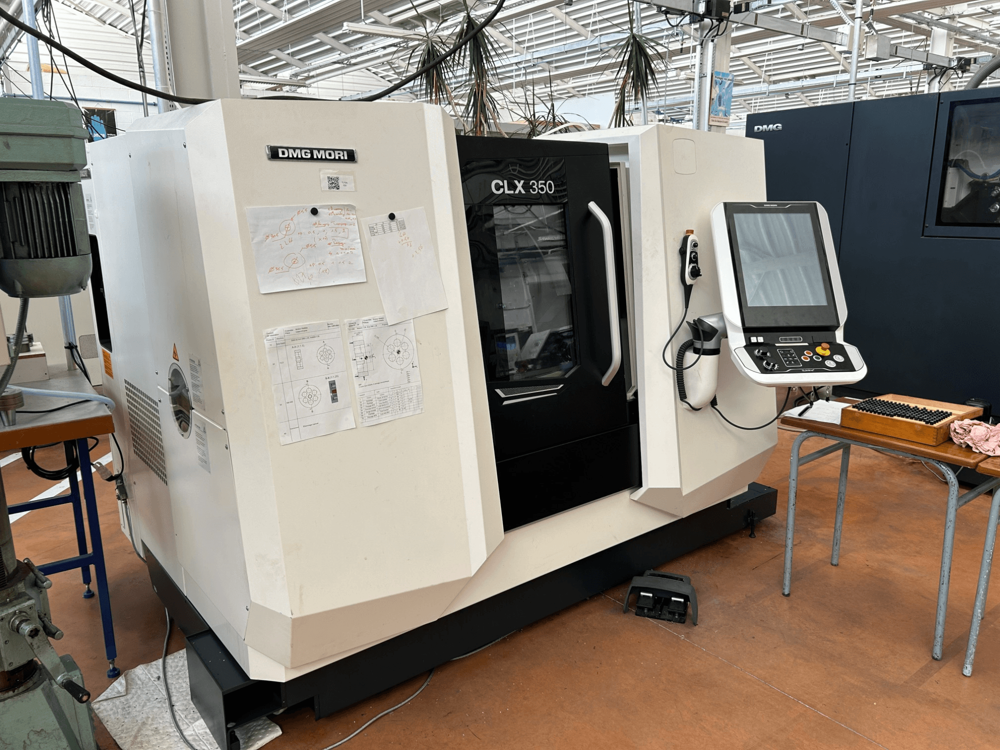 DMG MORI CLX 350 V4 horizontal turning machine, front view with control panel and technical documents attached.