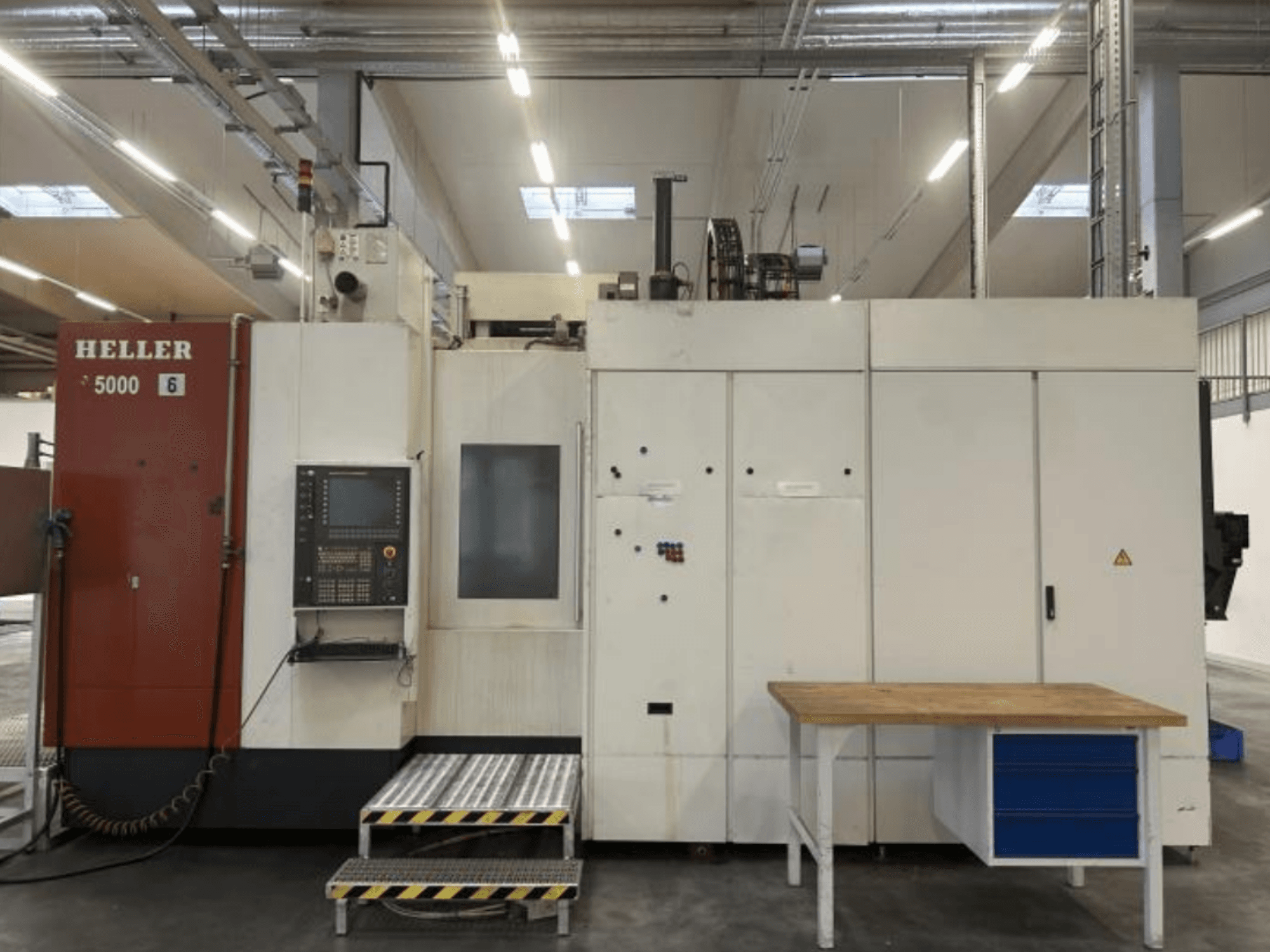 Front view of HELLER H5000 horizontal machining center with control panel, step-up platform, and adjacent work table.