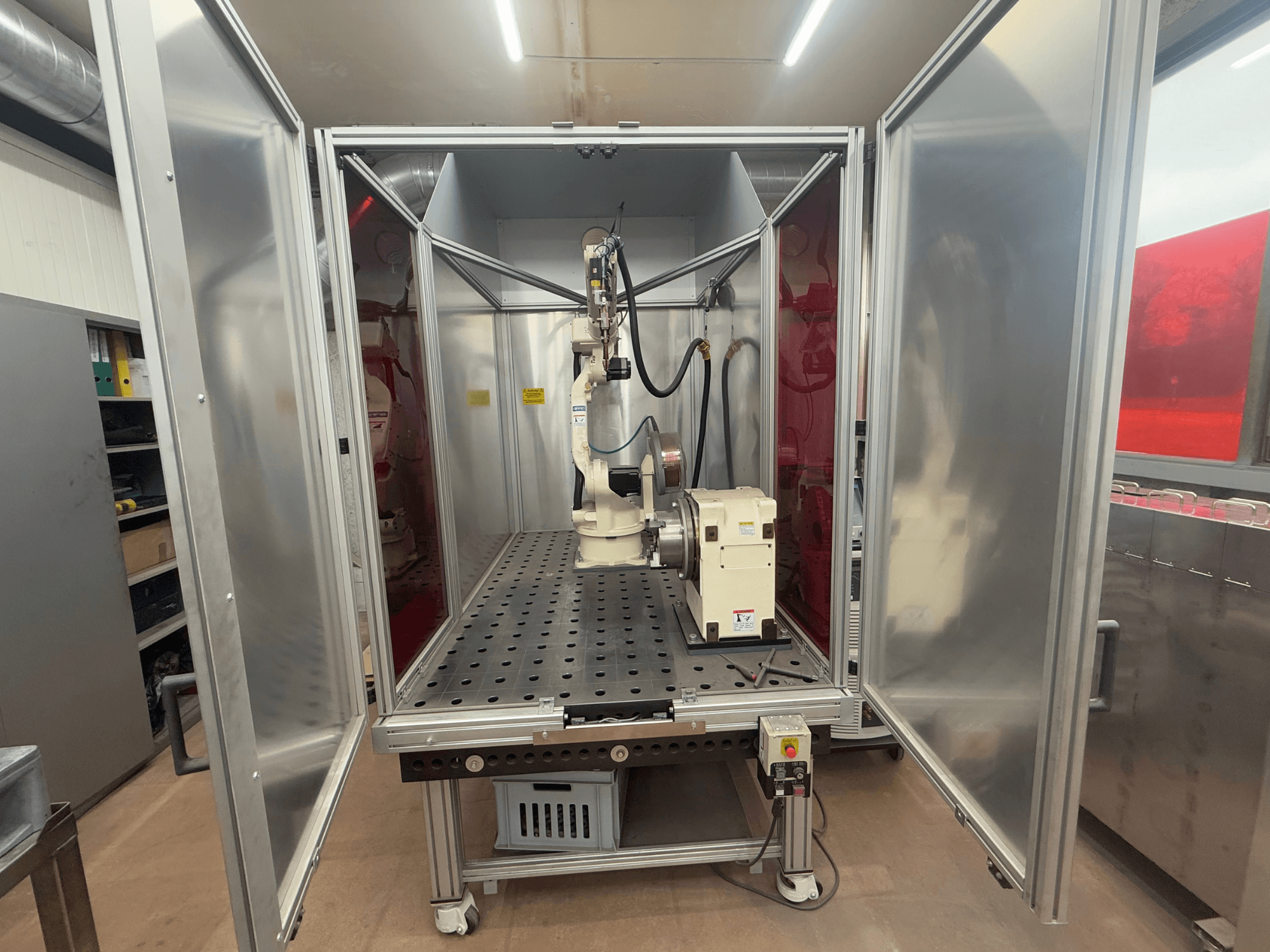 Welding robot OTC Daihen EASY ARC V02.04 in a metal enclosure, viewed from the front, showcasing its articulated arm and control panel.