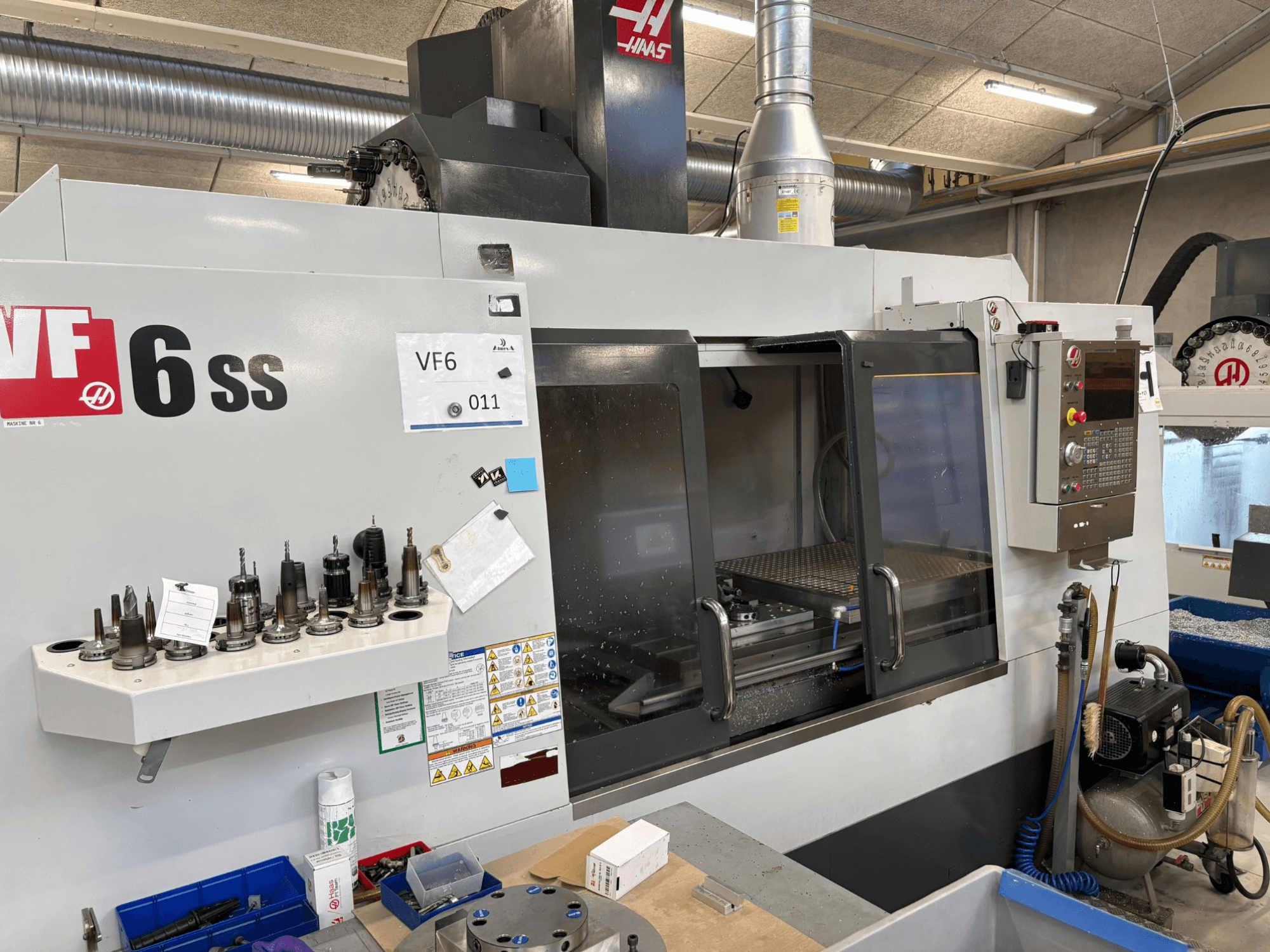 Haas VF-6 SS CNC milling machine, front view. Features various tools, control panel, and visible internal workspace.
