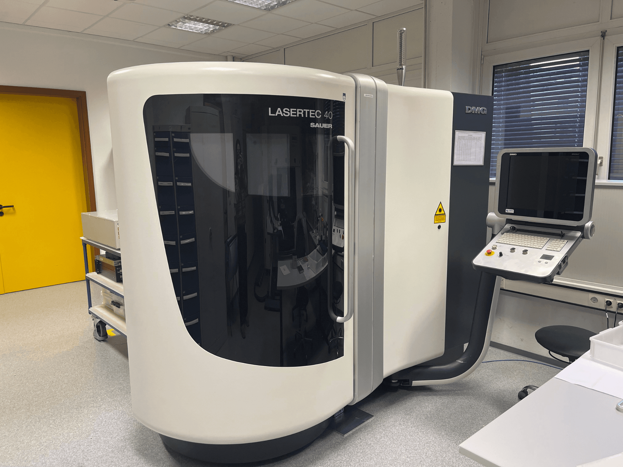 White LASERTEC 40 milling machine by DMG MORI, front view, features control panel and ergonomic design in a well-lit room.