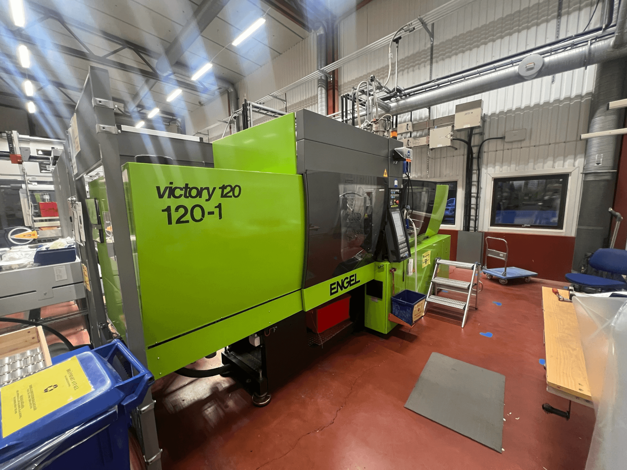 Green ENGEL Victory 120-1 injection molding machine, front view, with control panel and steps, in an industrial setting.