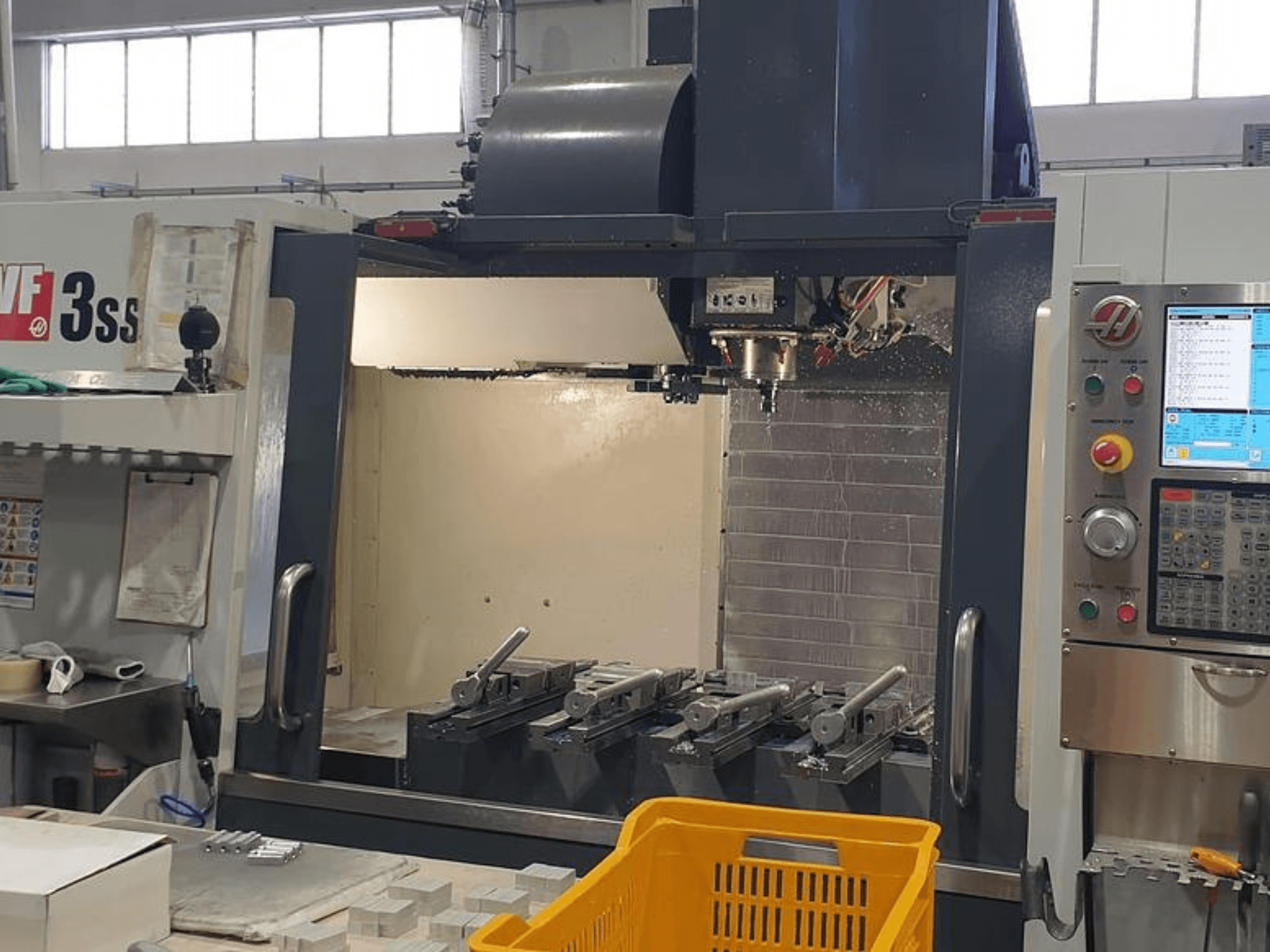 HAAS VF-3SS vertical machining center, front view with CNC control panel, tools, and orange basket.