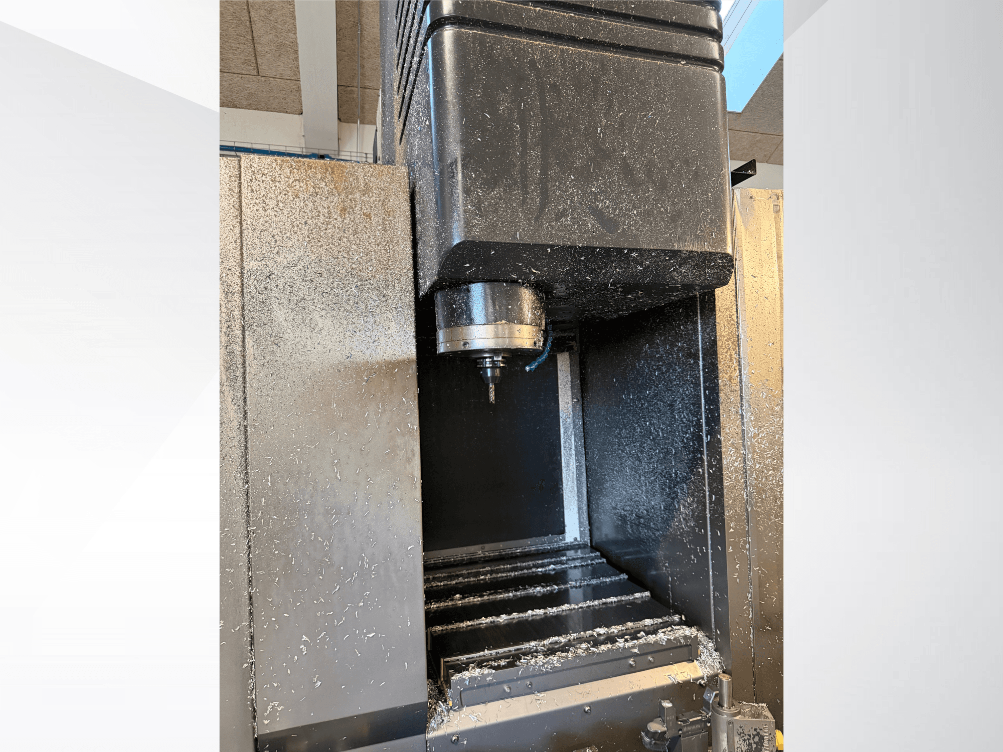 Mazak VTC 300C II vertical machining center, front view, showing spindle and chips from machining process.