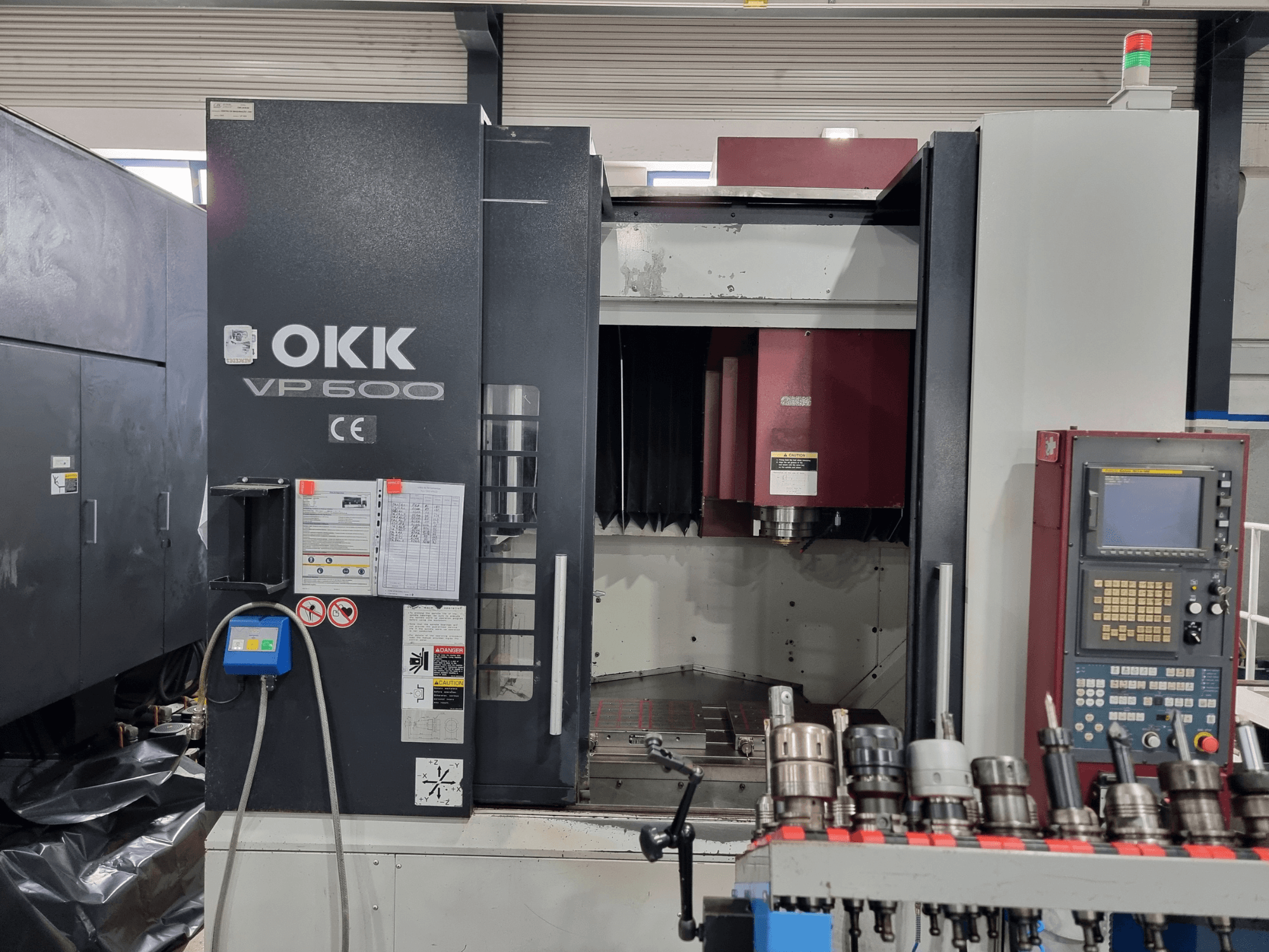 OKK VP600 vertical machining center from front view, showcasing the control panel and tool holders on a rack.