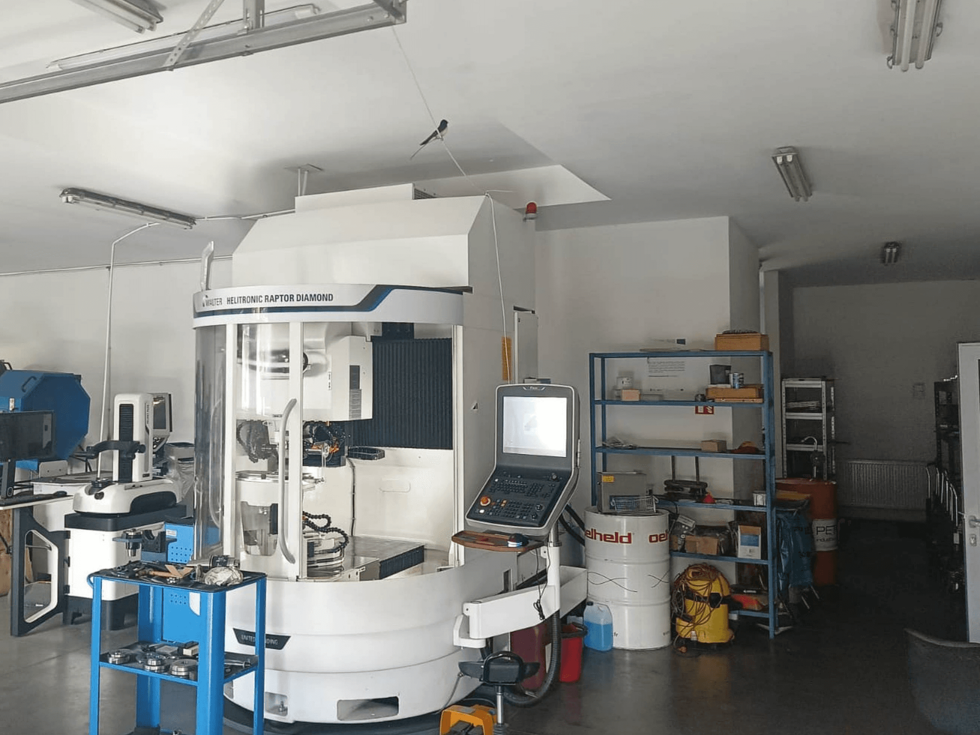 WALTER HELITRONIC RAPTOR DIAMOND cylindrical grinding machine in a workshop, side view with control panel and tools nearby.