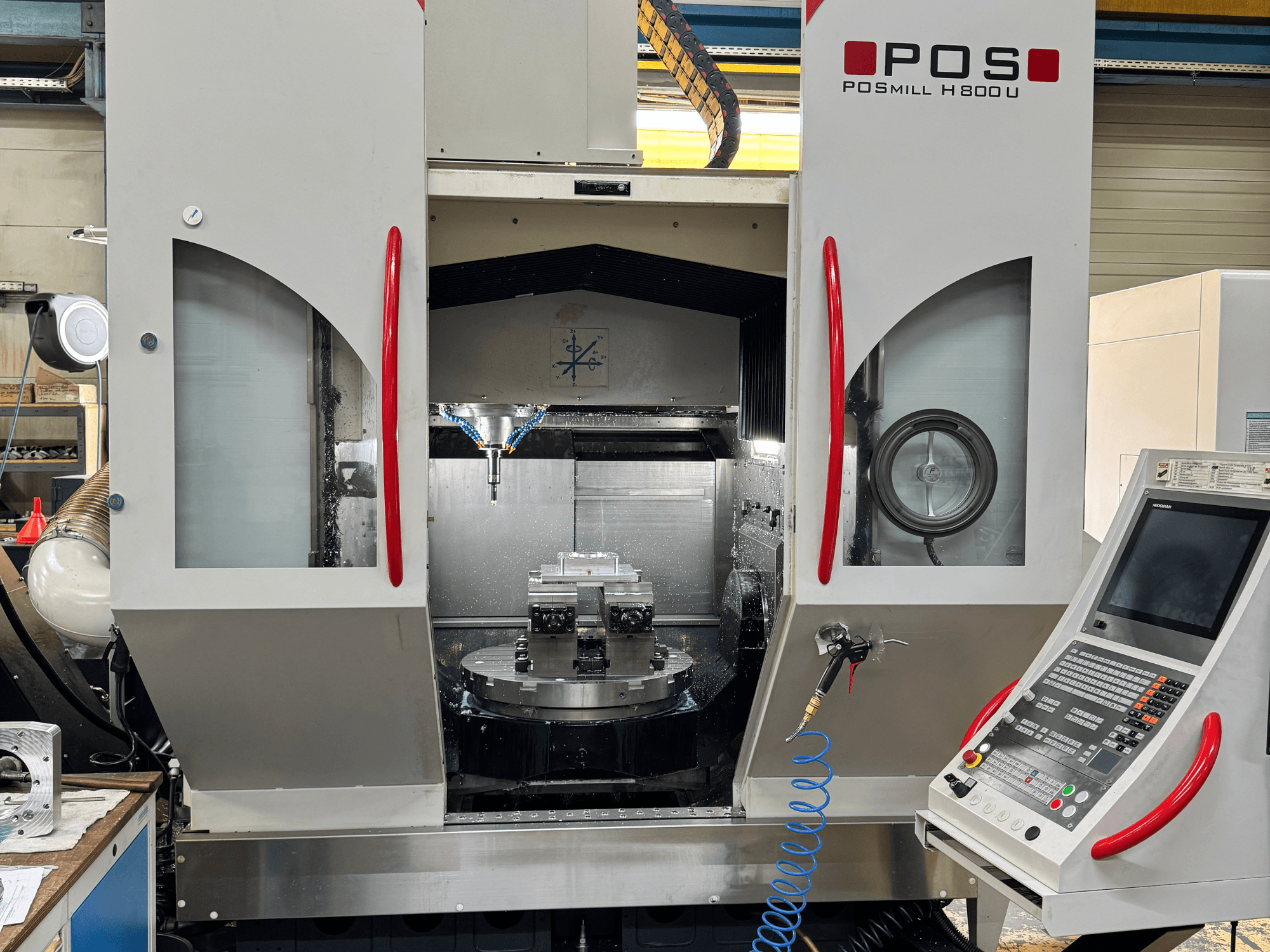 Vertical machining center POSmill H 800 U, front view showing internal components, coolant system, and control panel.