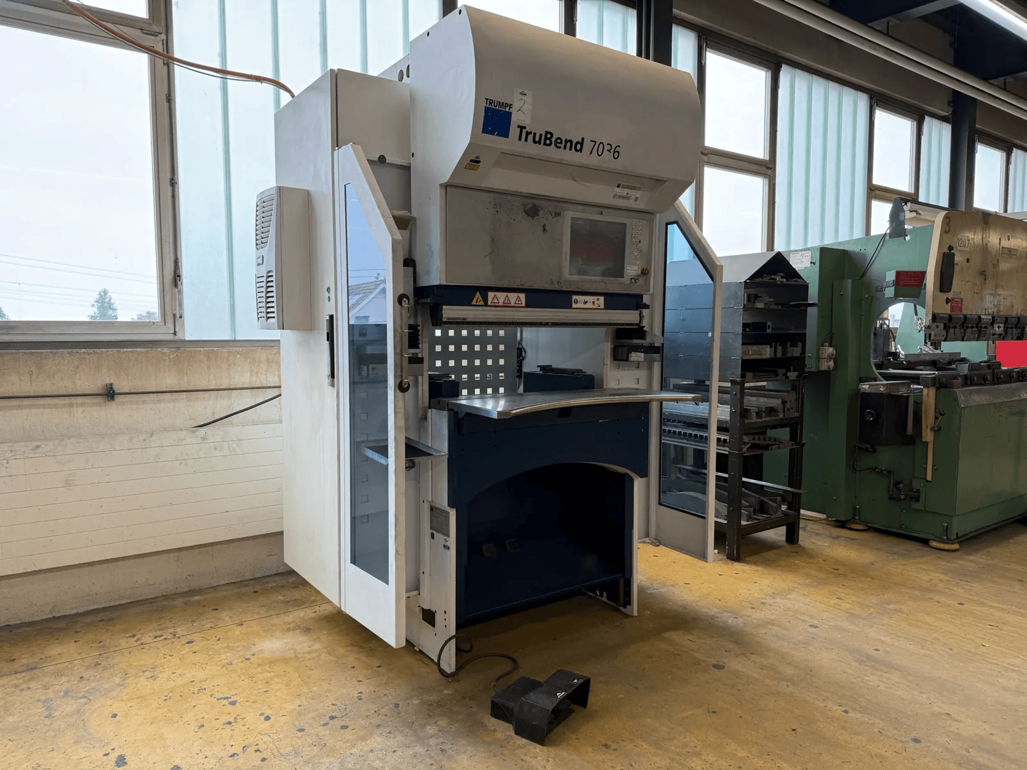 TRUMPF TruBend 7036 press brake in a workshop, front view with open door, showing control panel and bending area.