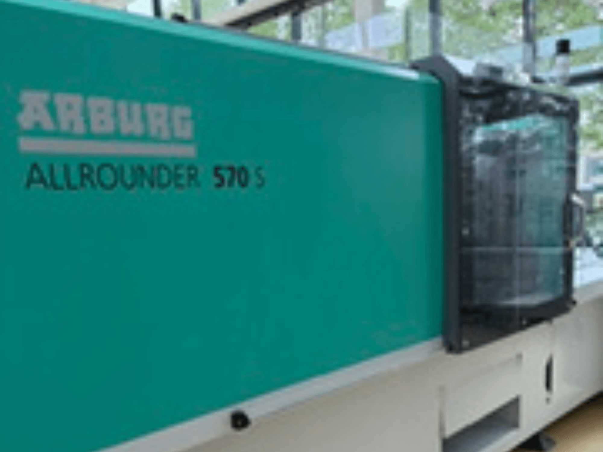 Front view of Arburg ALLROUNDER 570 S 1600-290, featuring a teal exterior and injection unit, showing part of the machine design.