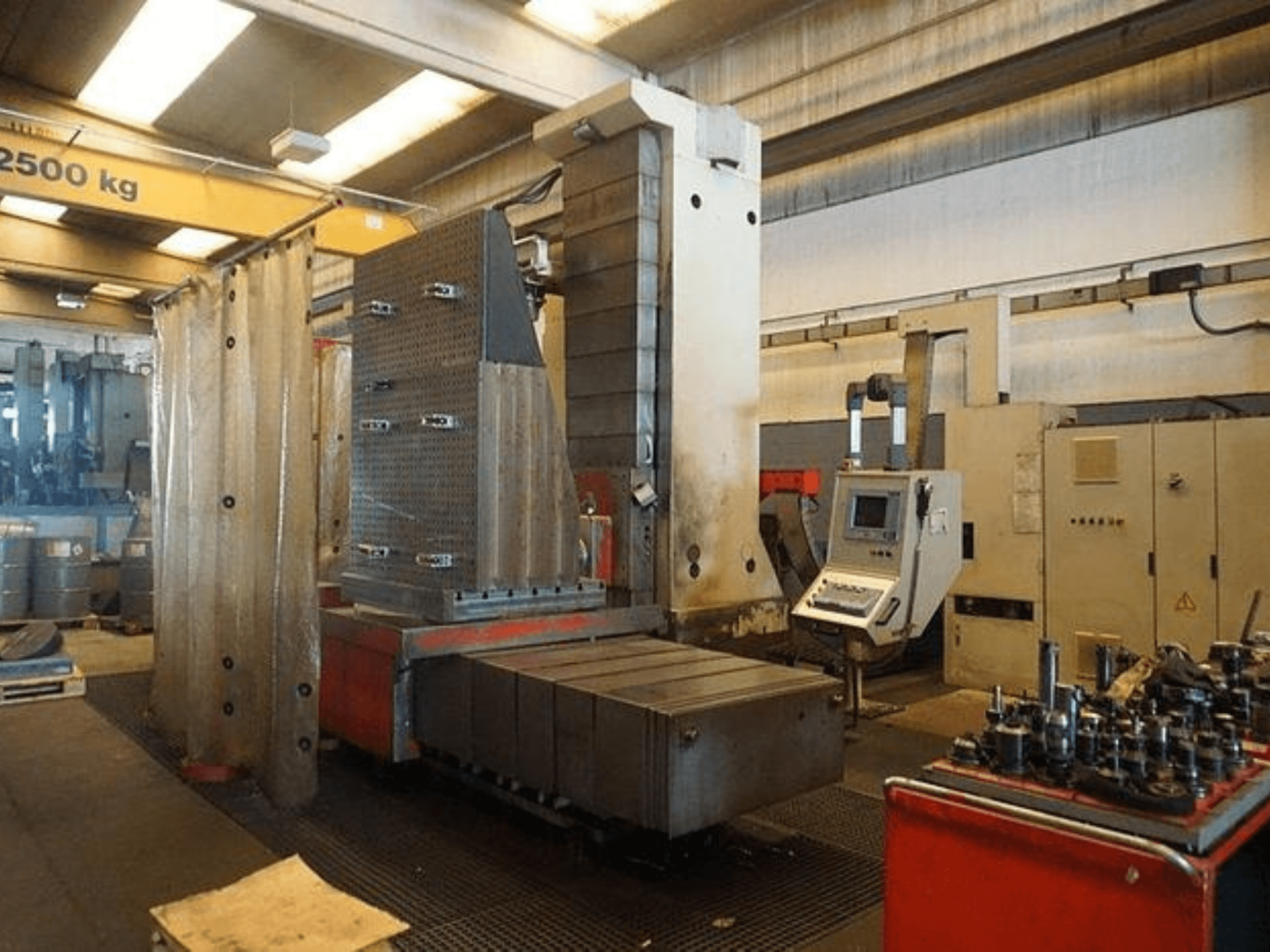 Industrial milling machine with touchscreen control and large work table, viewed from the front in a workshop setting.