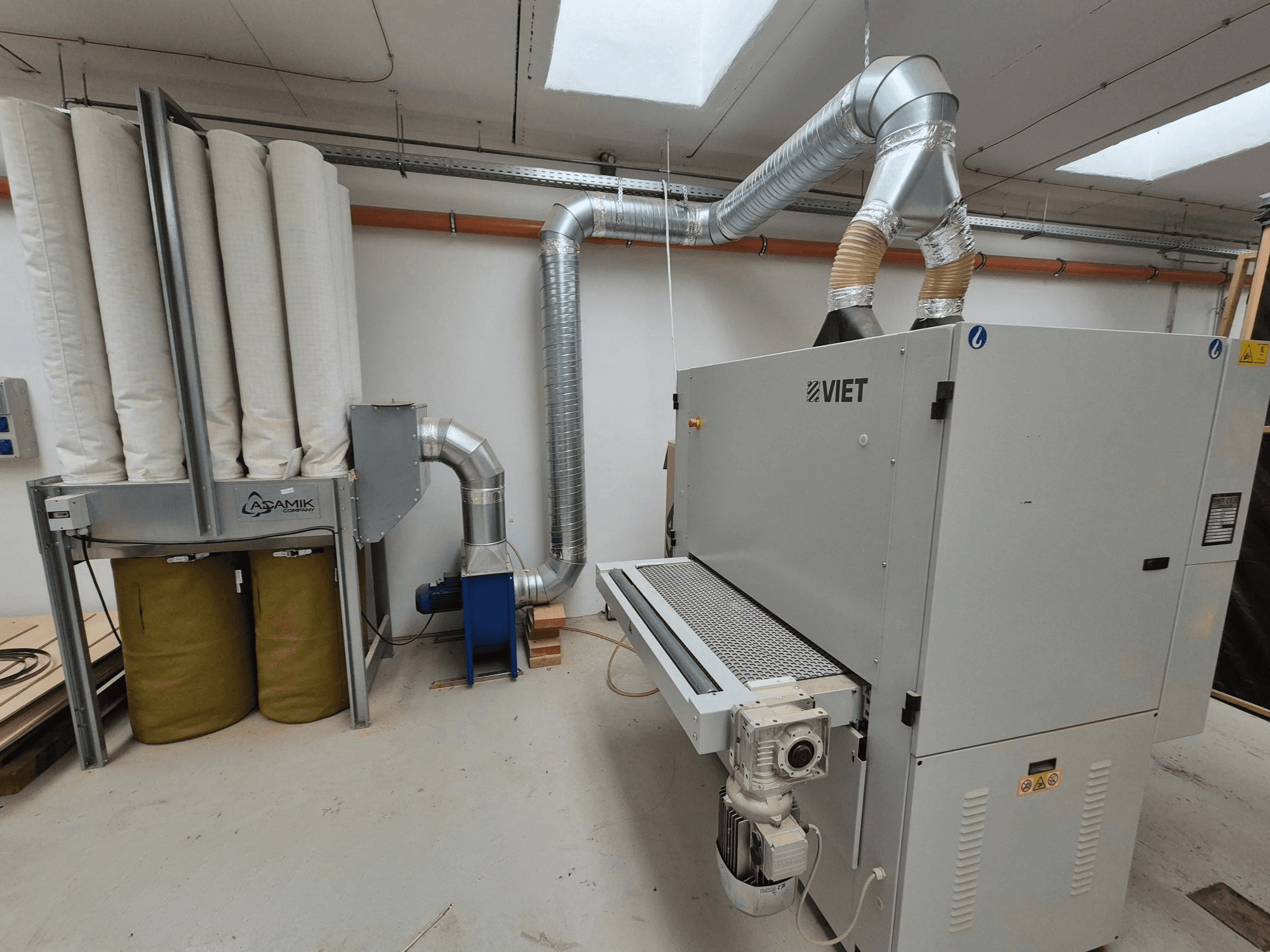 Viet dust extraction system featuring cylindrical filters and a silver exhaust, viewed from the front in a workshop setting.