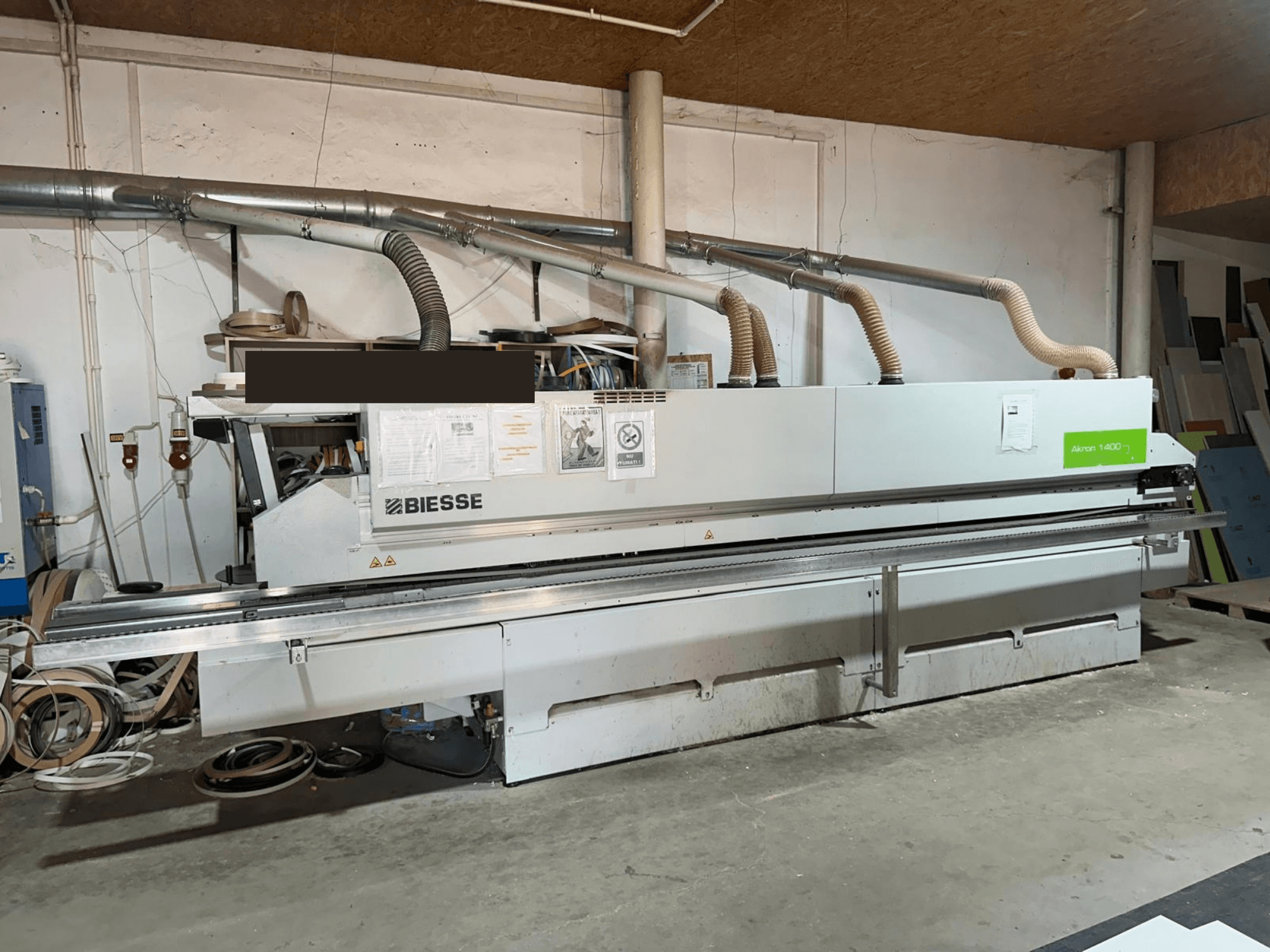 BIESSE AKRON 1440 A edgebander, front view, featuring visible operation panel and dust extraction components in workshop setting.